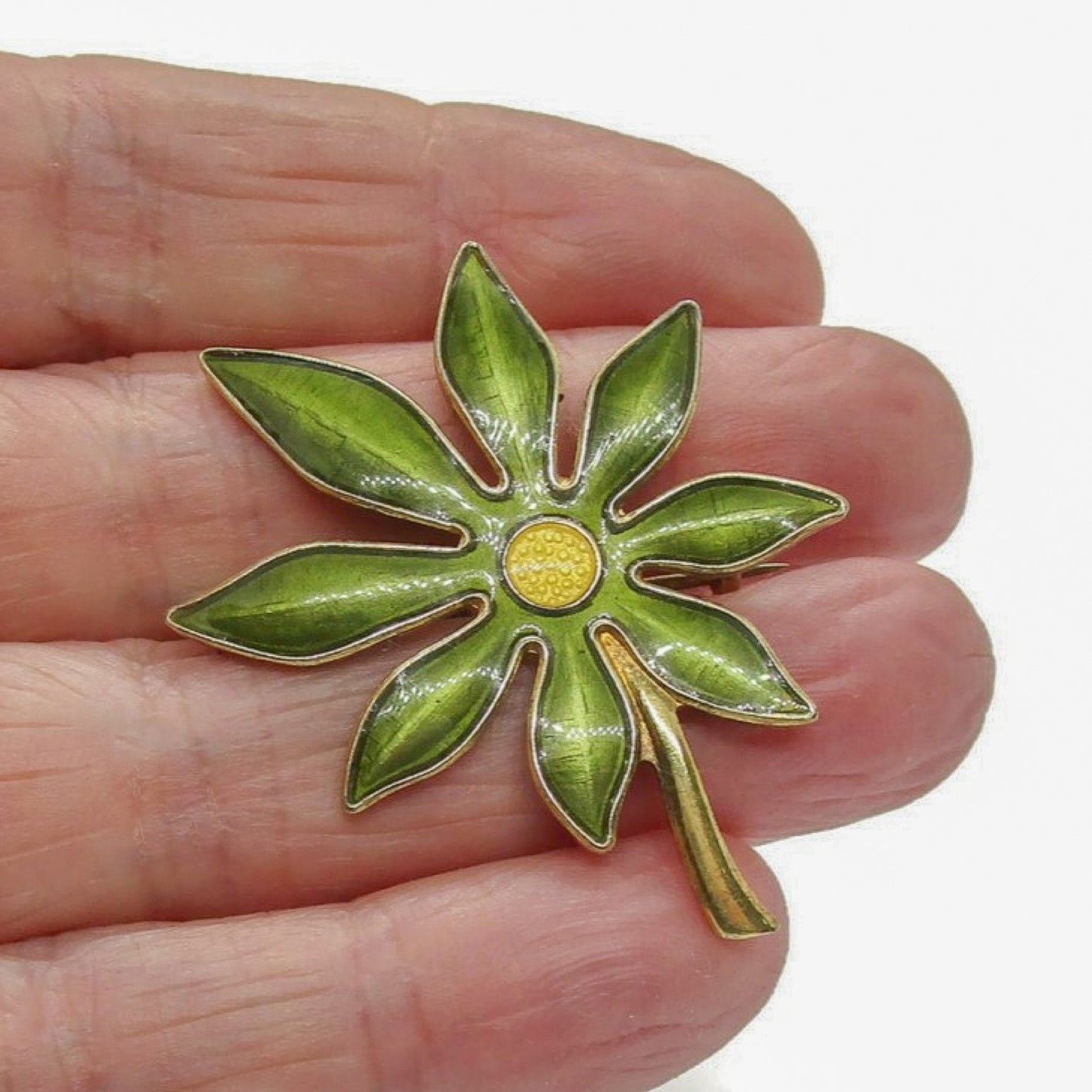 Aksel Holmsen sterling silver gilt and enamel daisy brooch being held in a hand
