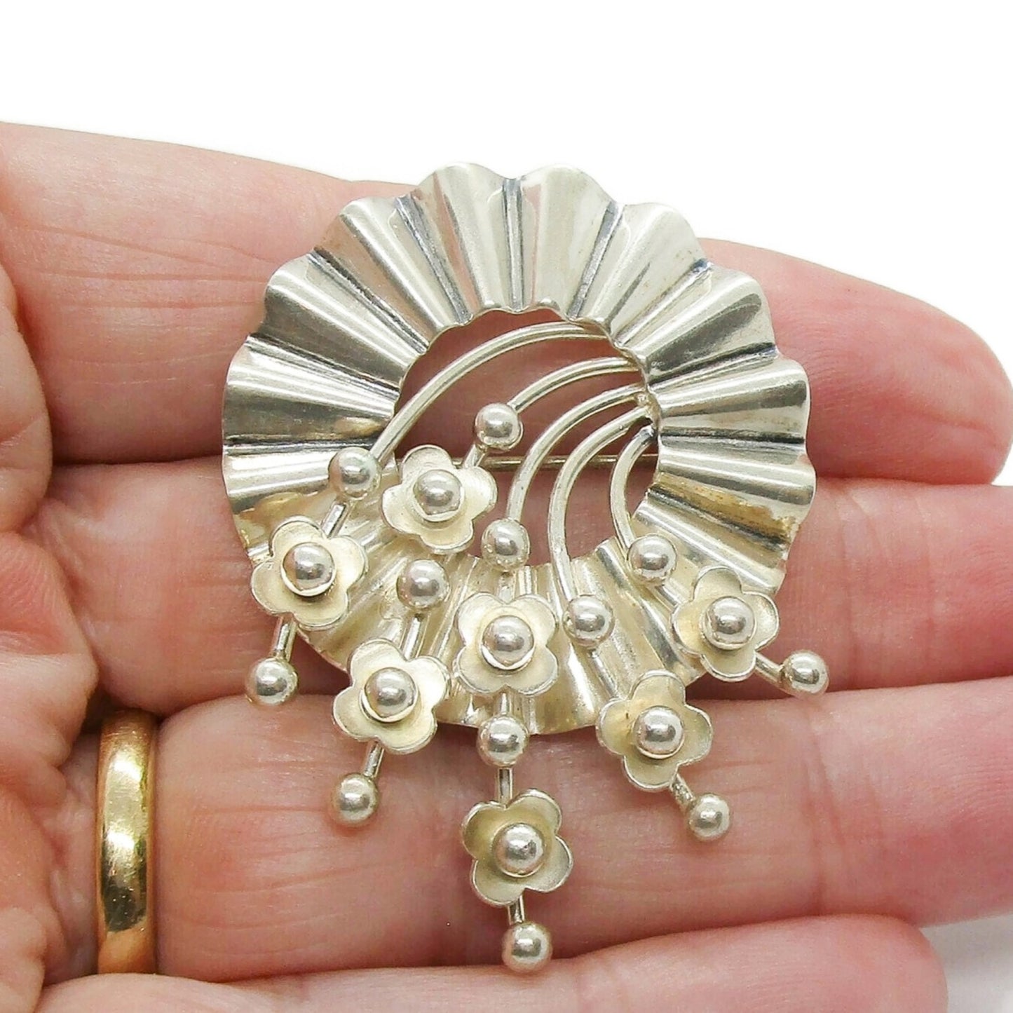 John Lauritzen 830 silver circular floral brooch held in the hand