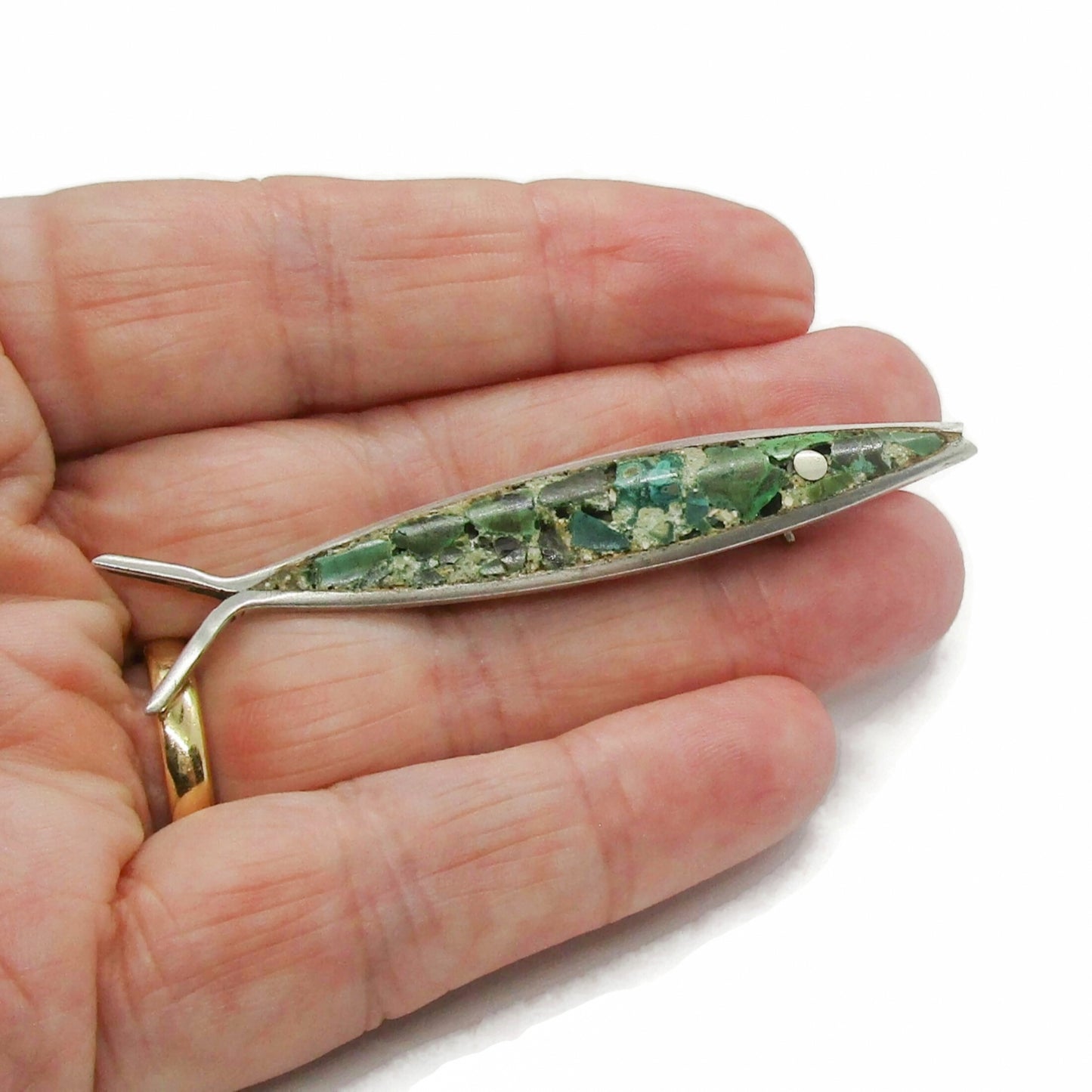 Mexican sterling silver and crushed turquoise fish brooch shown held in a hand