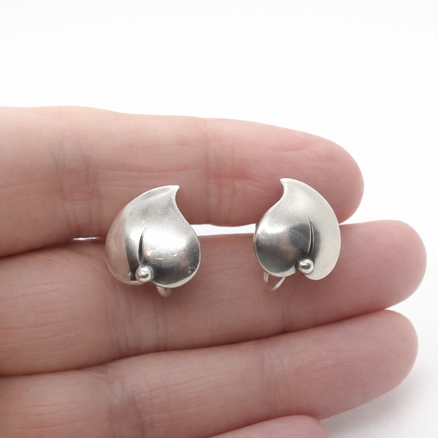 A pair of vintage sterling silver screw back leaf earring by Niels Erik From, Denmark shown held in a hand