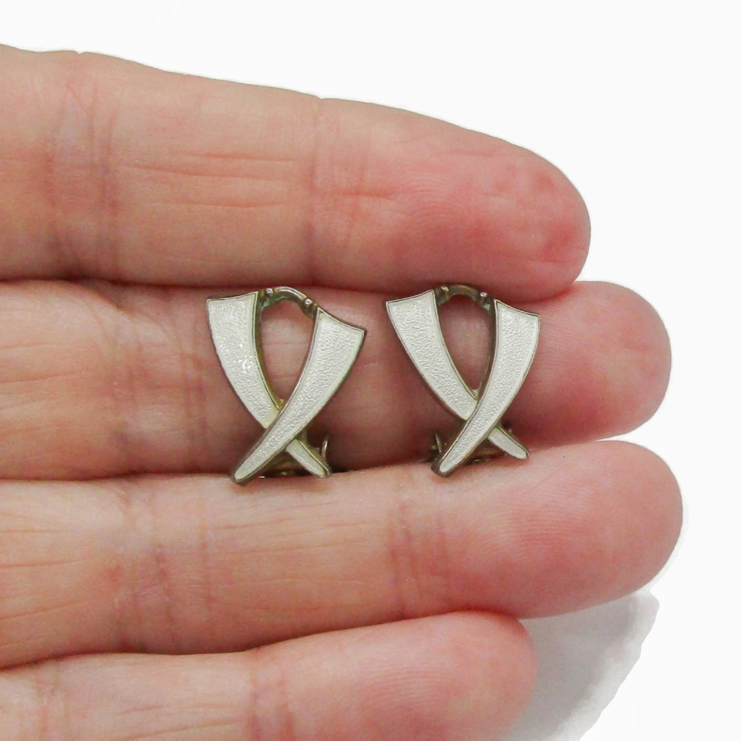A pair of Aksel Holmsen Norway sterling silver and enamel clip on earrings in a cross design shown held in a hand