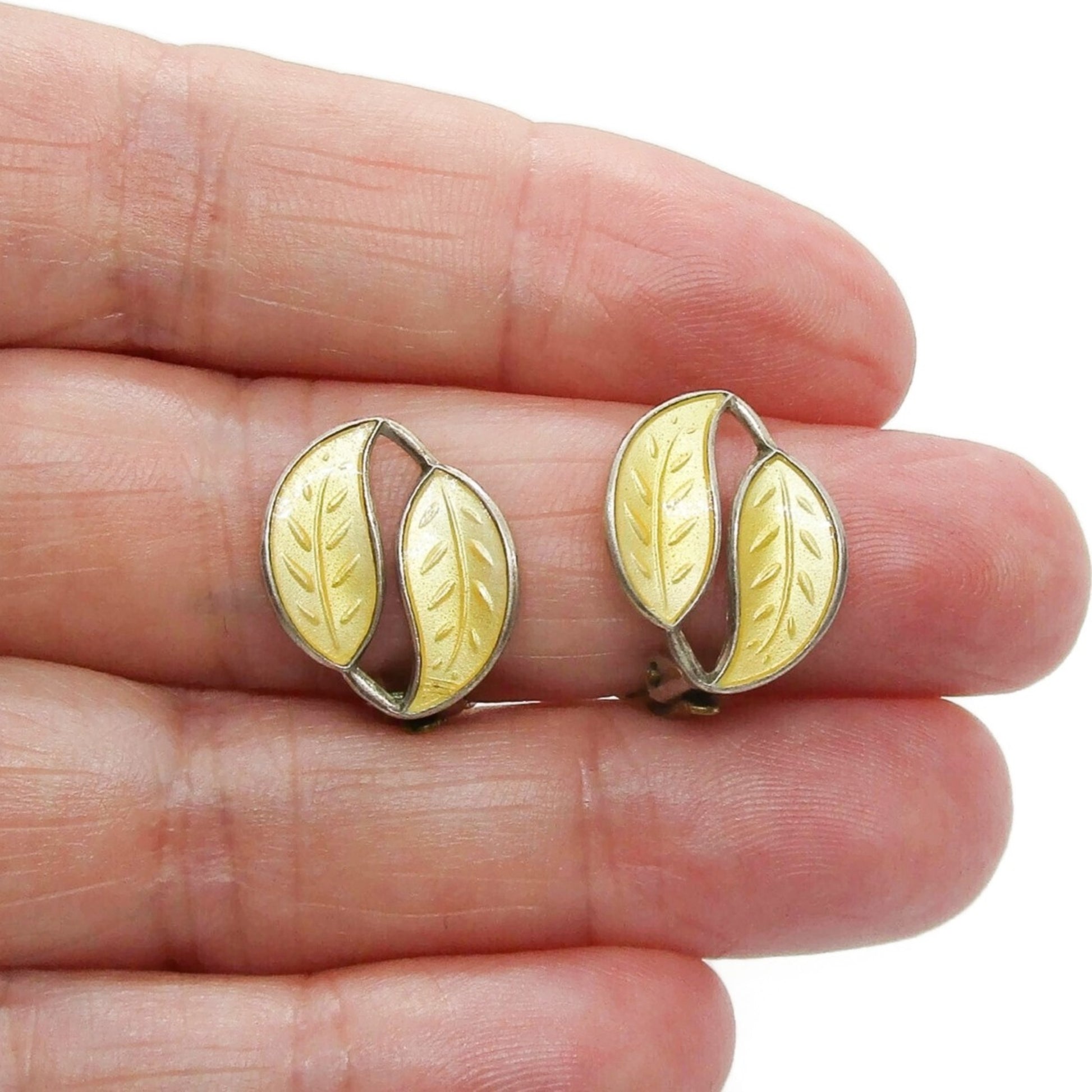 A pair of David Andersen Norway small yellow enamel double leaf clip on earrings shown held in a hand