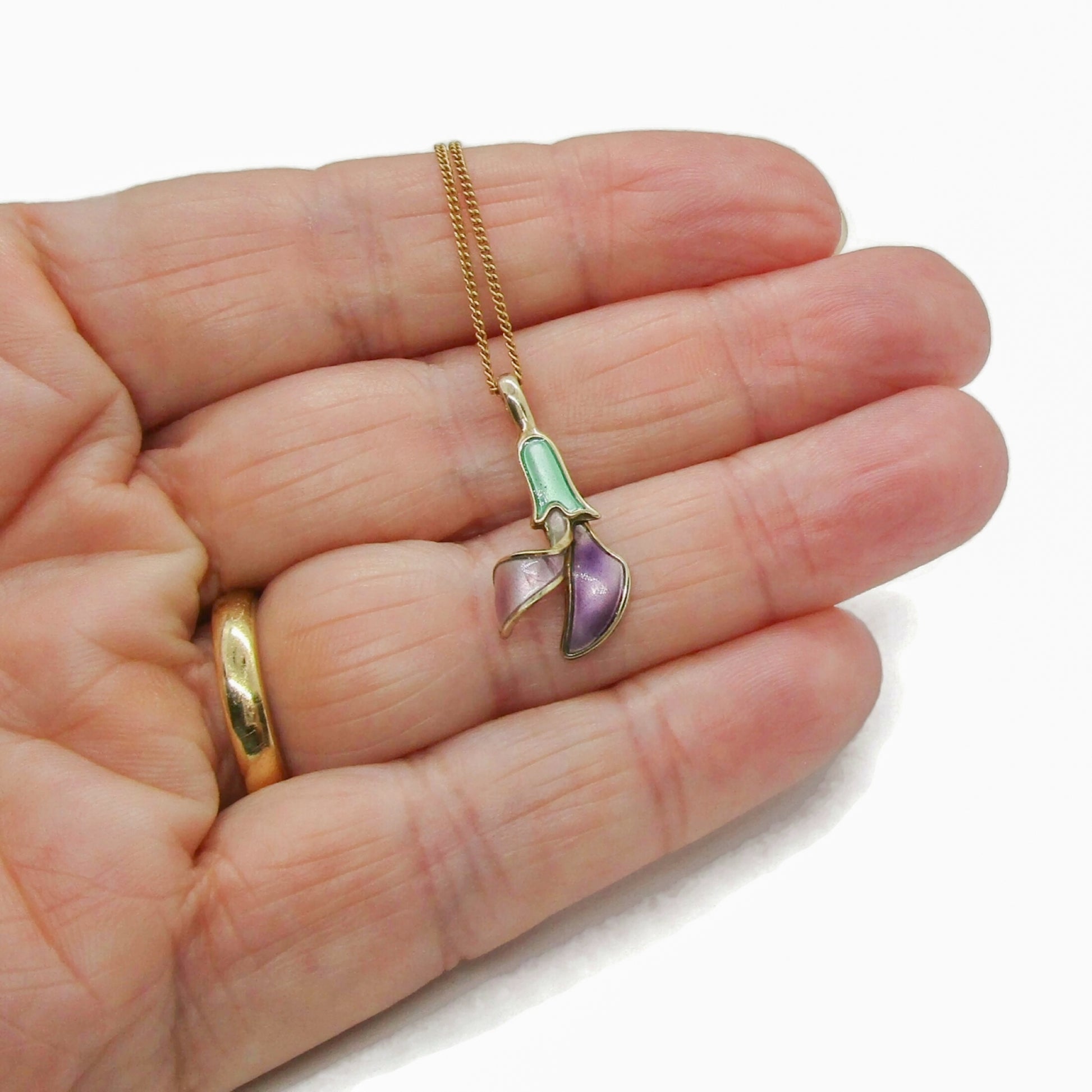 A dainty David Andersen Norway enamel and sterling silver gilt flower pendant held in a hand
