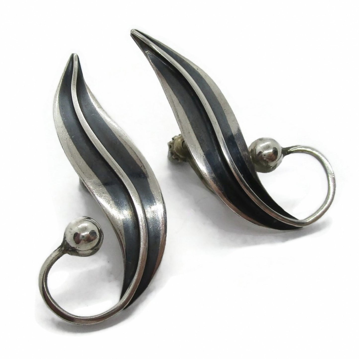 A pair of sterling silver screw on earrings in a curvy design by Delfino Mexico shown on an angle