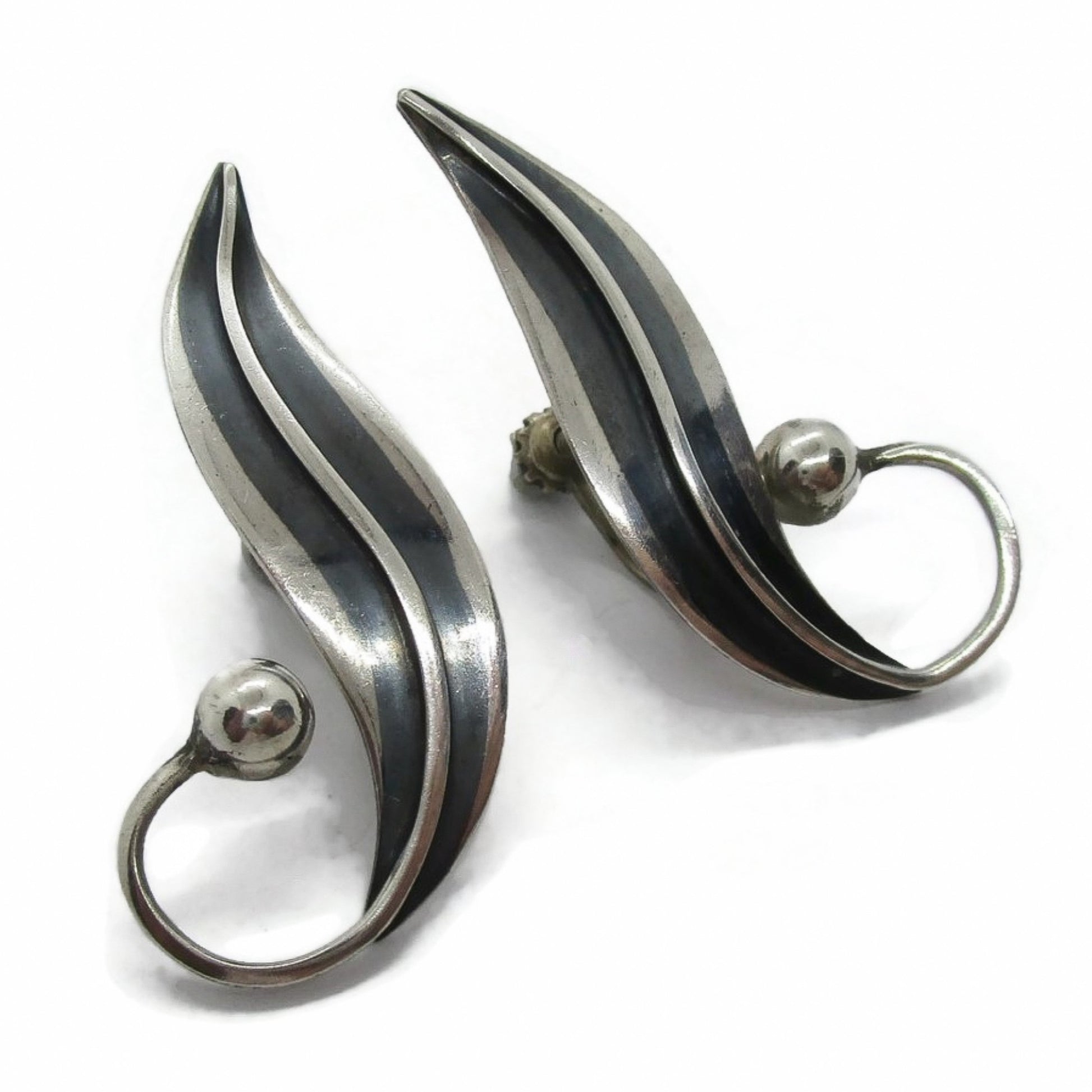 A pair of sterling silver screw on earrings in a curvy design by Delfino Mexico shown on an angle