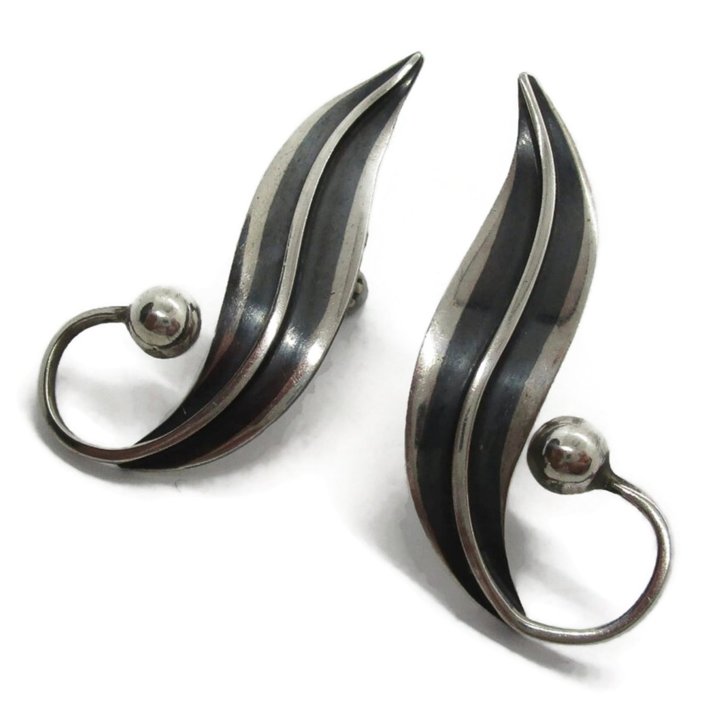 Close up angled view of a pair of sterling silver screw on earrings in a curvy design by Delfino Mexico