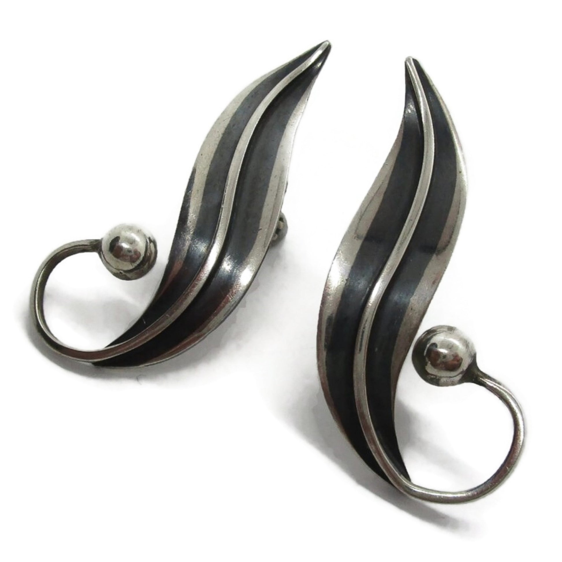 Close up angled view of a pair of sterling silver screw on earrings in a curvy design by Delfino Mexico