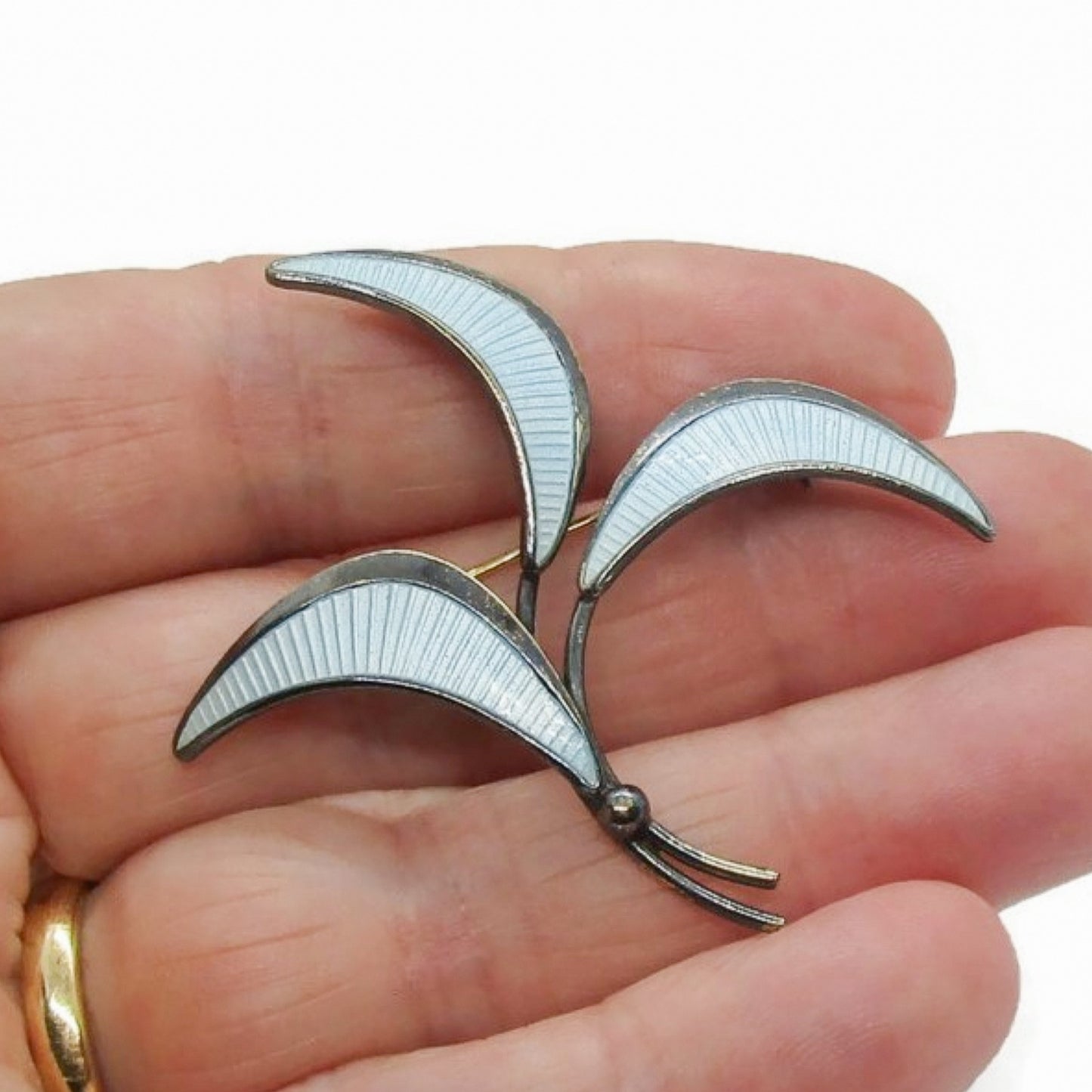 E Dragsted Denmark blue enamel and sterling silver brooch shown held in a hand
