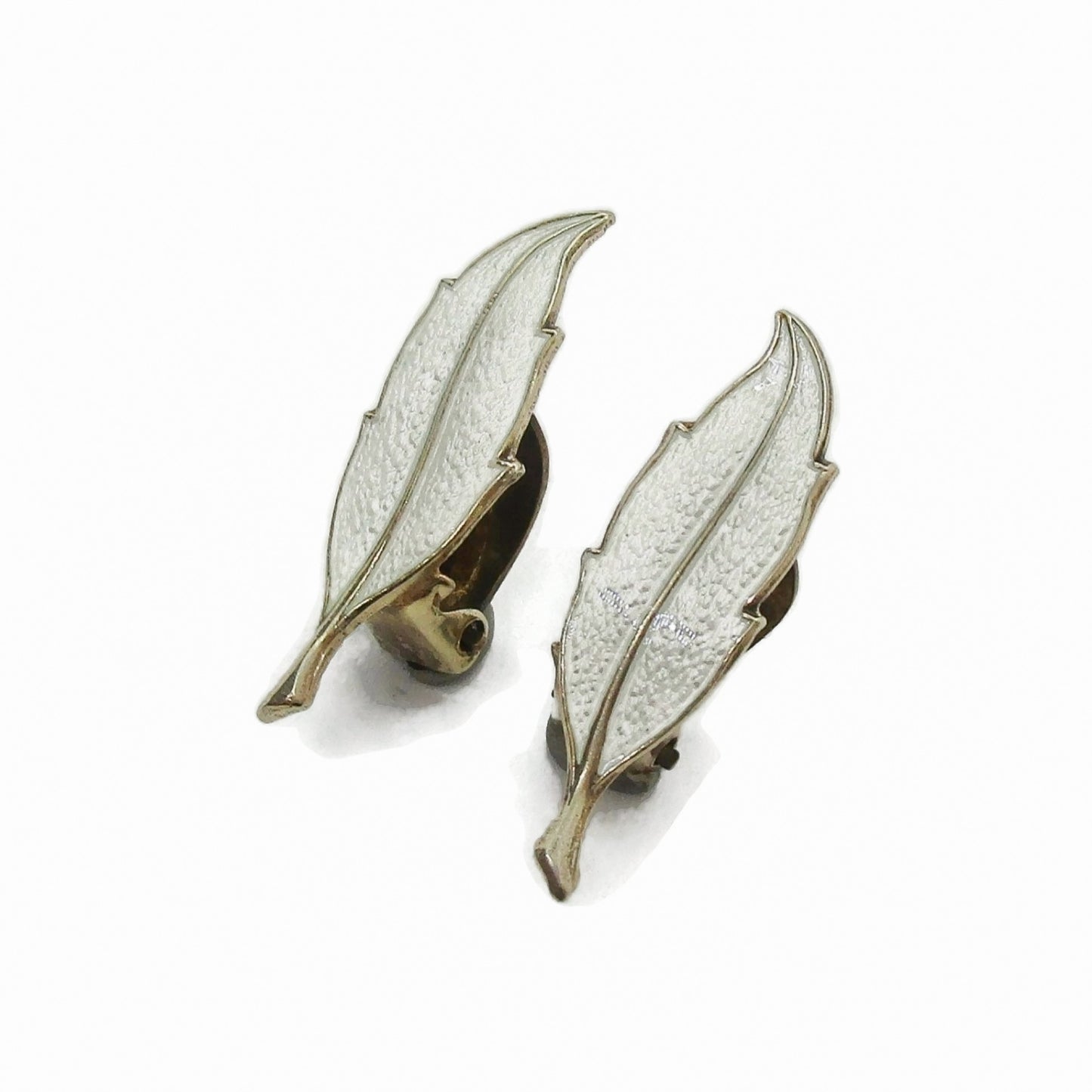 Angled view of a pair of Finn Jensen Norway sterling silver gilt and white enamel leaf clip on earrings
