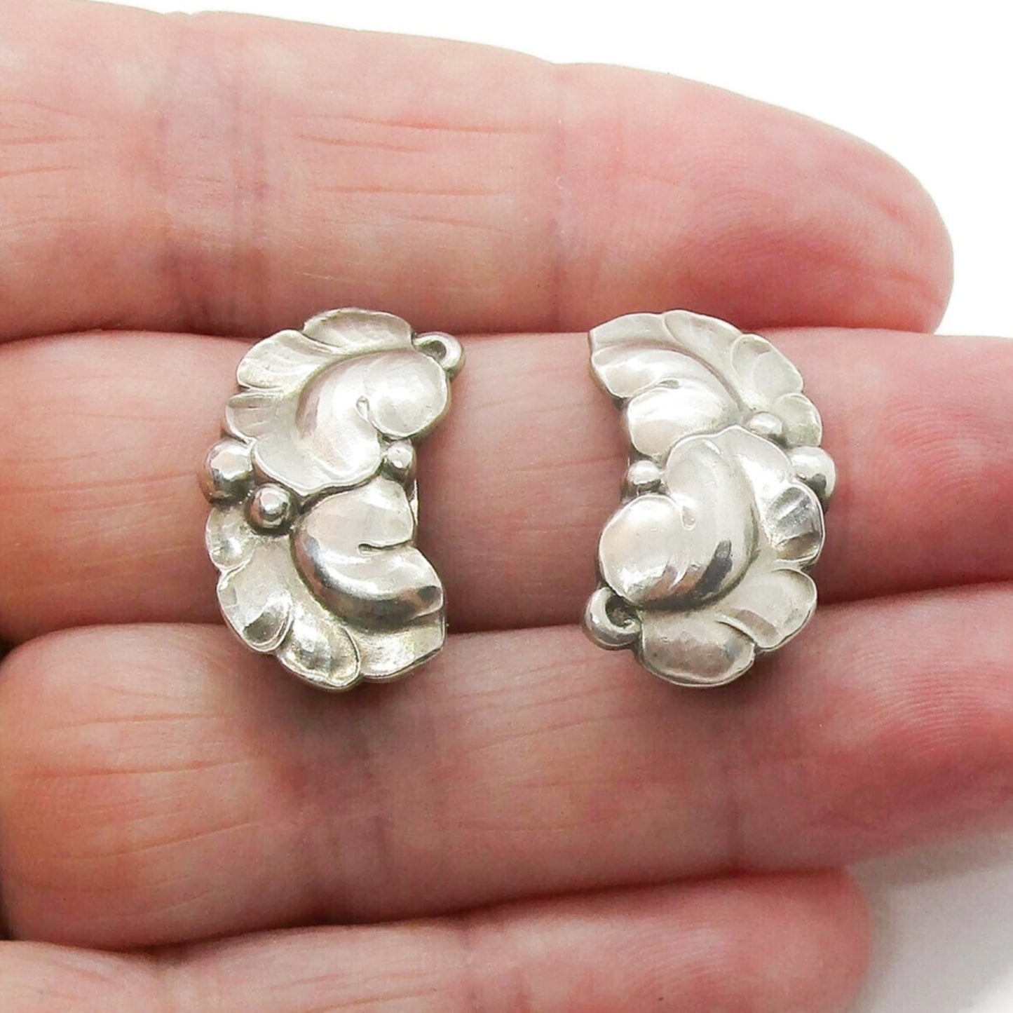 A pair of Georg Jensen sterling silver clip on earrings design number 50A shown held in a hand