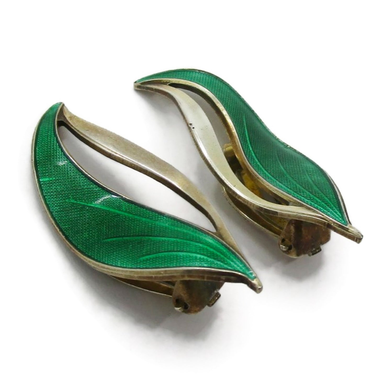 Angled view of a pair of Hroar Prydz Norway green enamel and sterling silver gilt leaf shaped clip on earrings