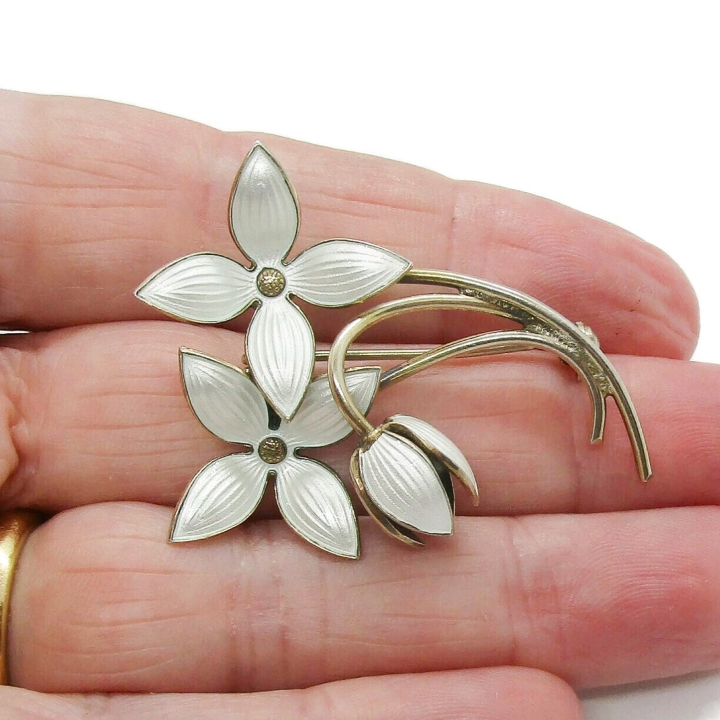 Ivar Holth Norway sterling silver gilt and white enamel flower spray brooch shown held in a hand