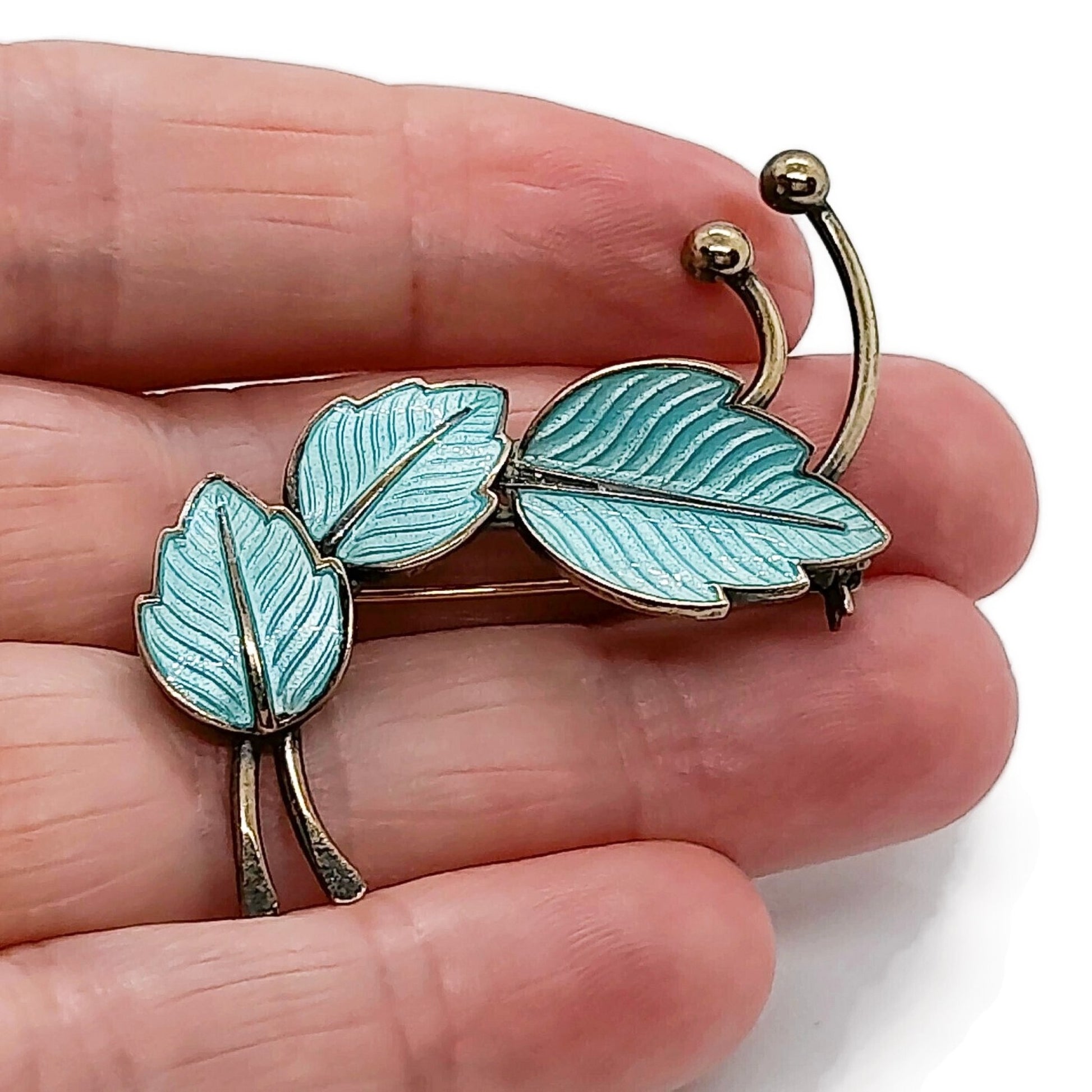Jemax Denmark blue enamel and sterling silver gilt leaf brooch shown held in a hand