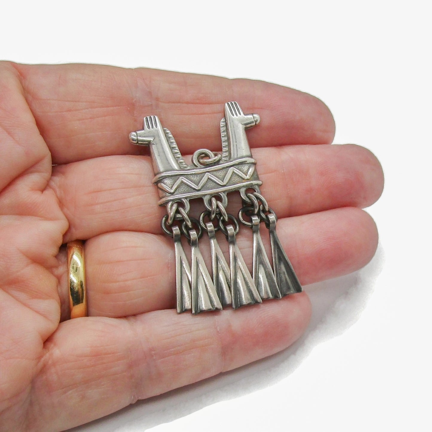 A Kalevala Koru Finland sterling silver double headed horse pendant held in a hand