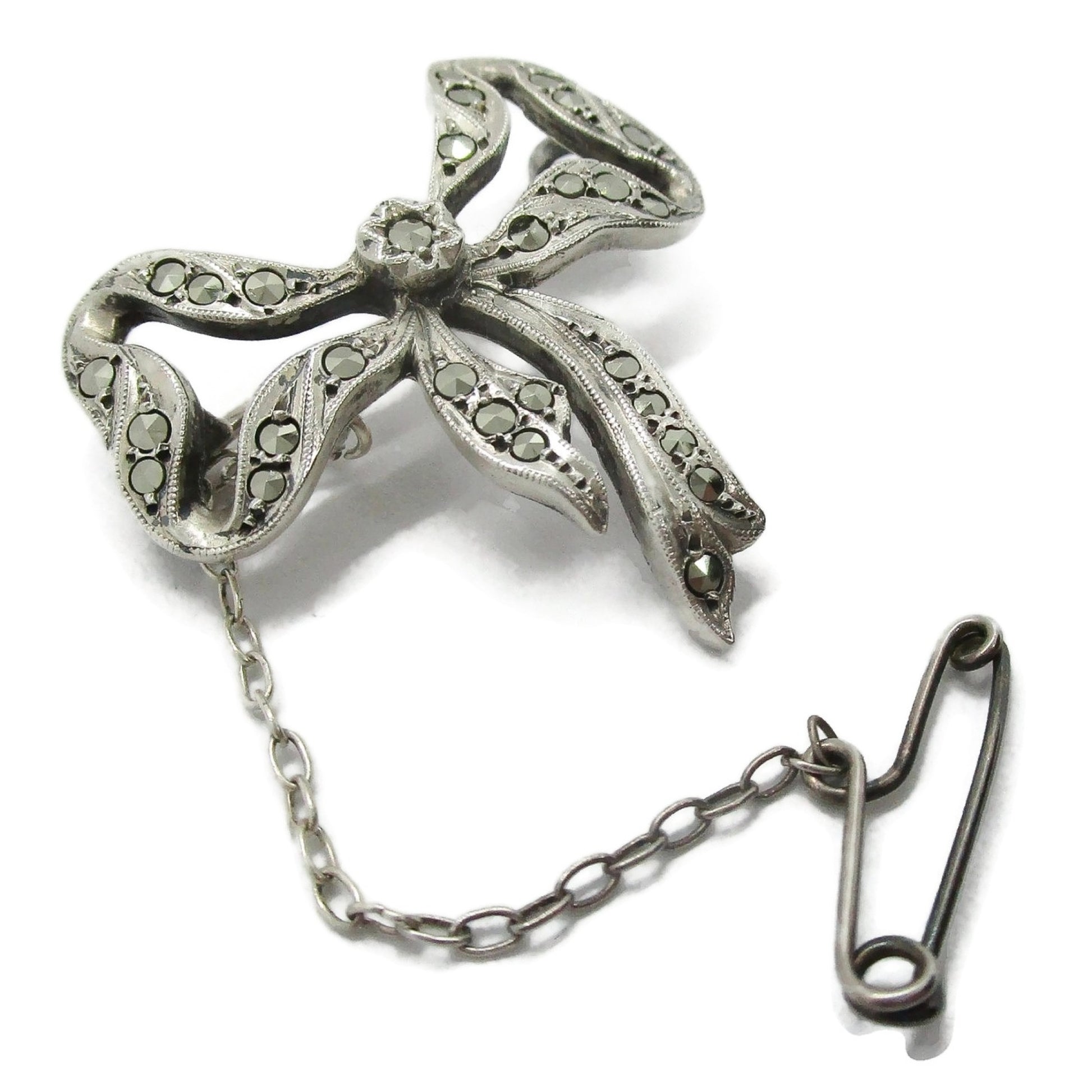Lega Australia marcasite and sterling silver bow brooch with safety chain shown on an angle