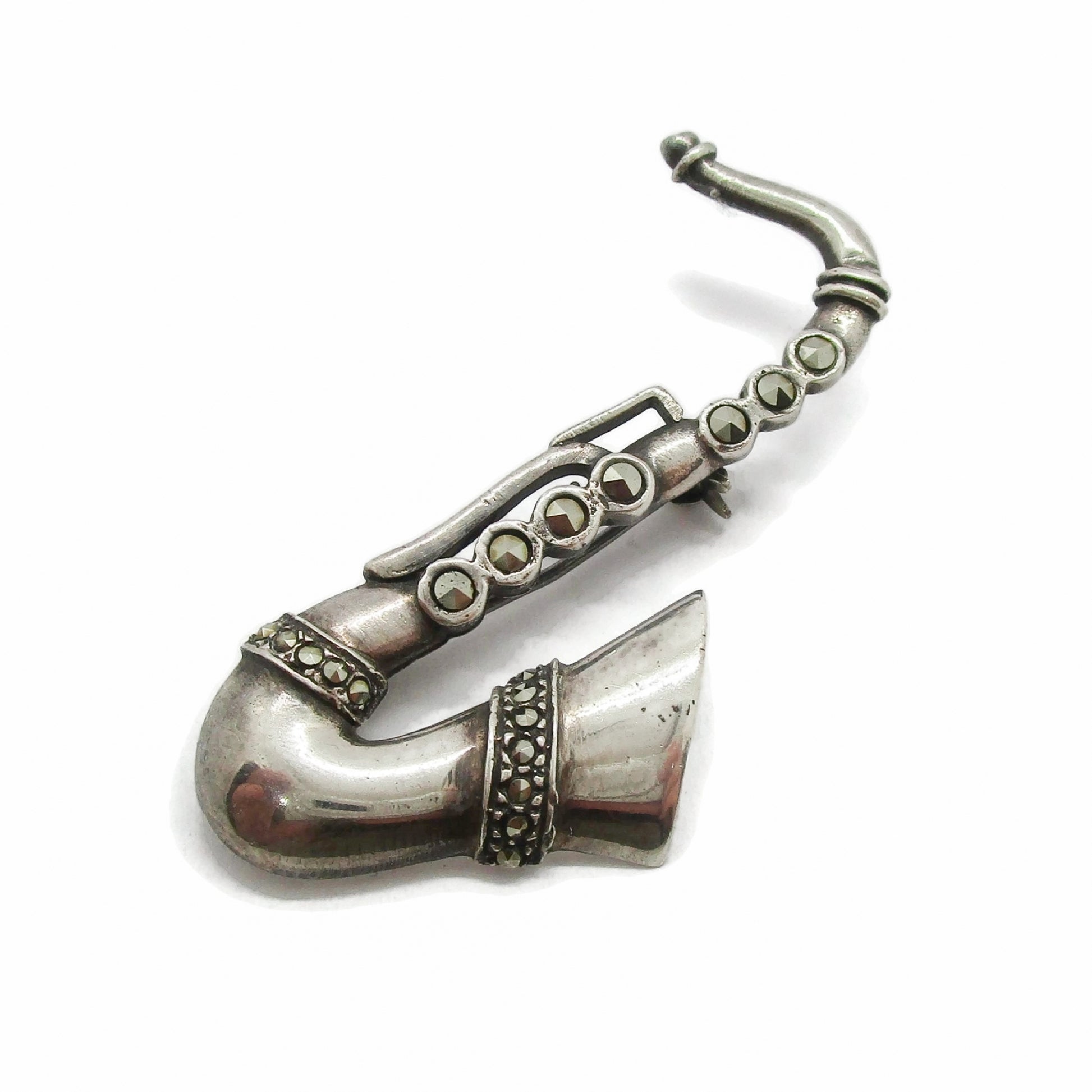 Vintage sterling silver and marcasite saxophone brooch on a white background