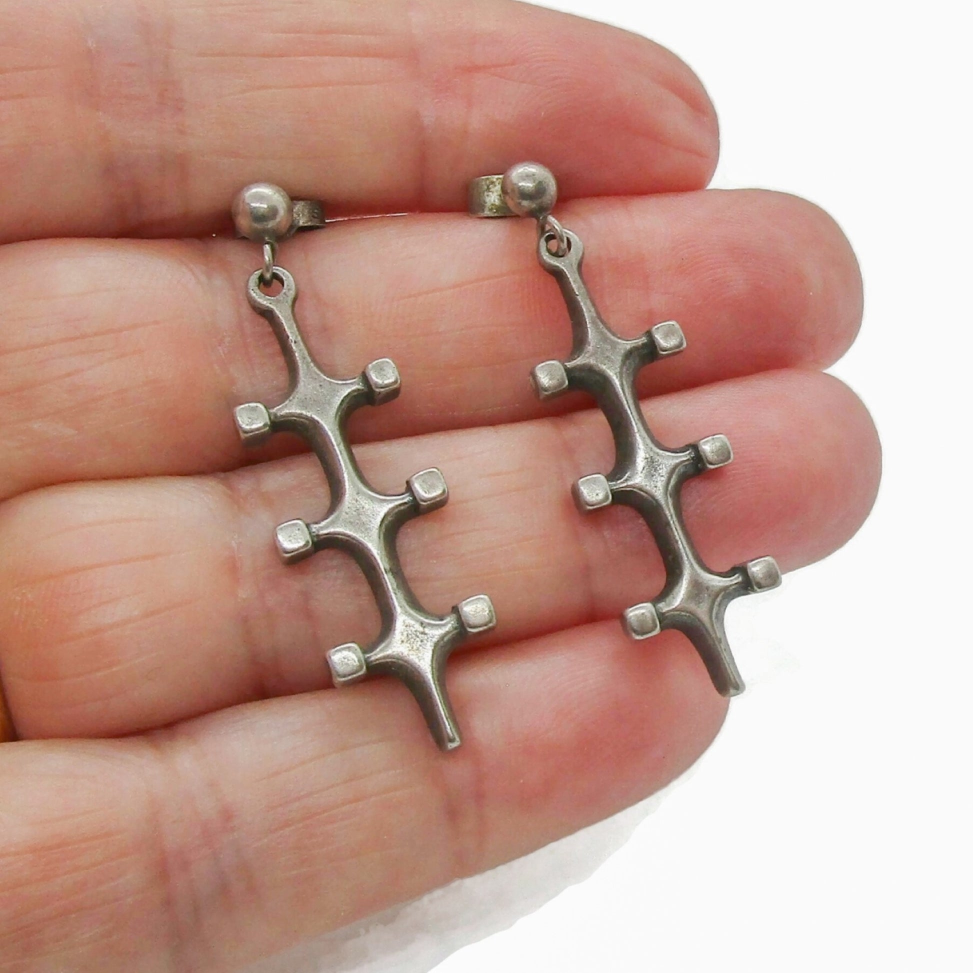 A pair of Marianne Berg Troll series sterling silver dangle earrings shown held in a hand
