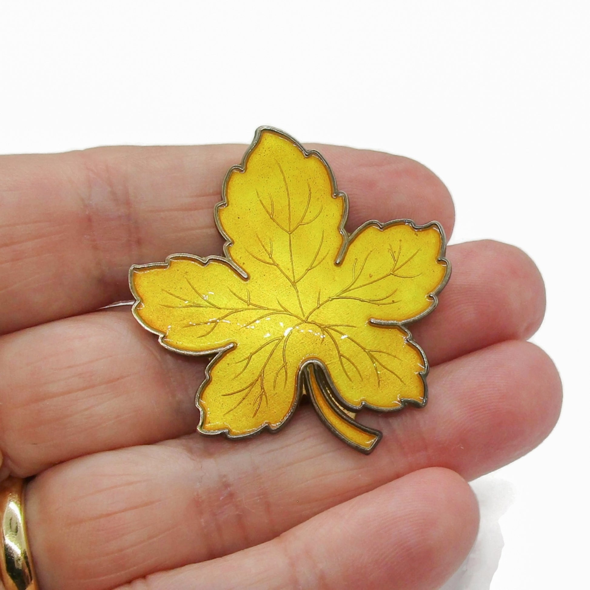 Meka Denmark sterling silver and yellow enamel maple leaf brooch shown held in a hand