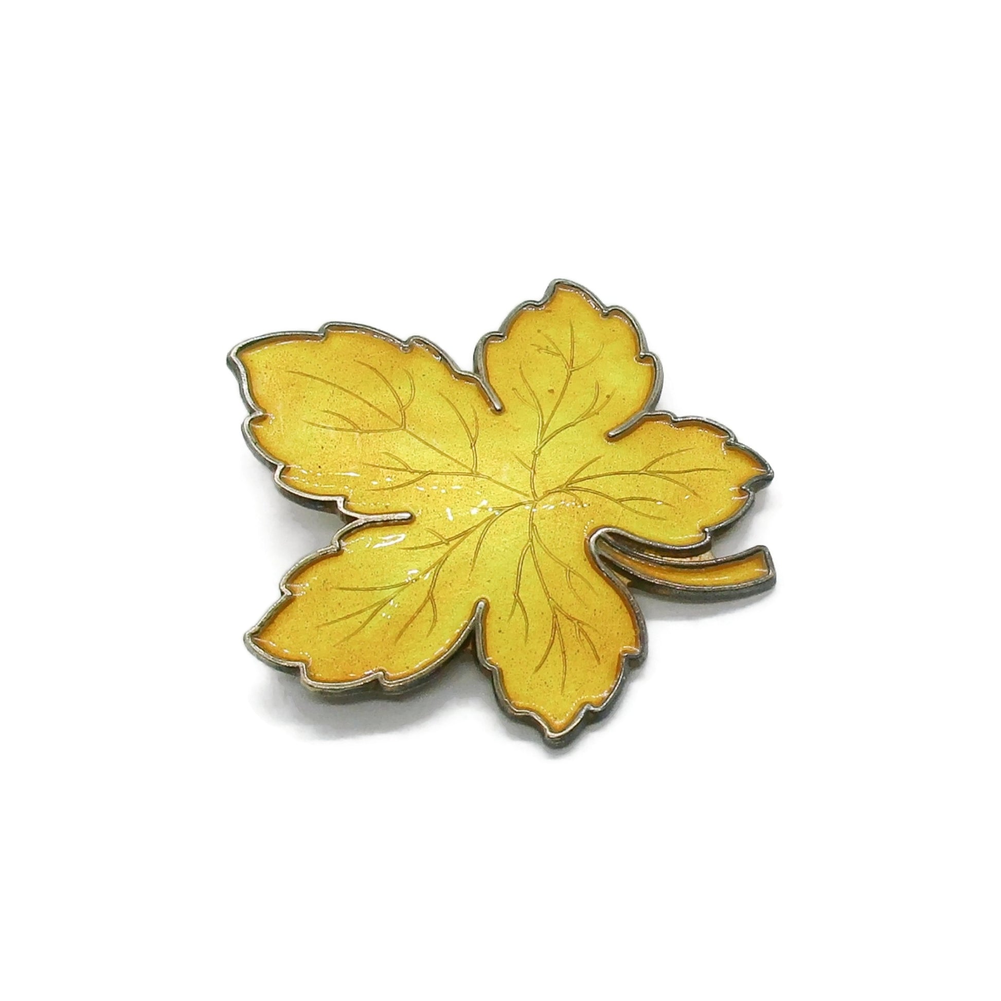 Meka Denmark sterling silver and yellow enamel maple leaf brooch shown on an angle