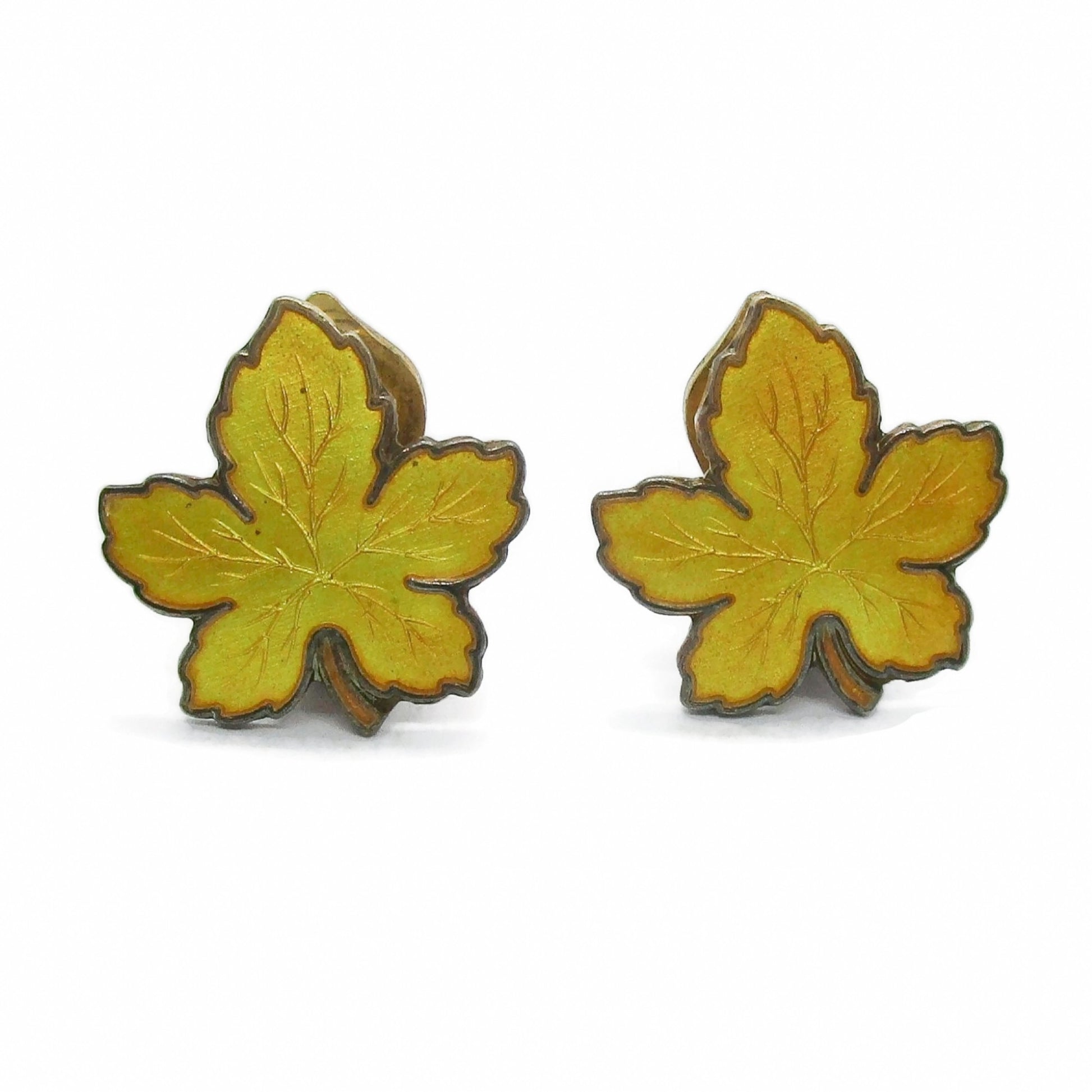 Front view of a pair of Meka Denmark yellow guilloche enamel and sterling silver gilt maple leaf clip on earrings