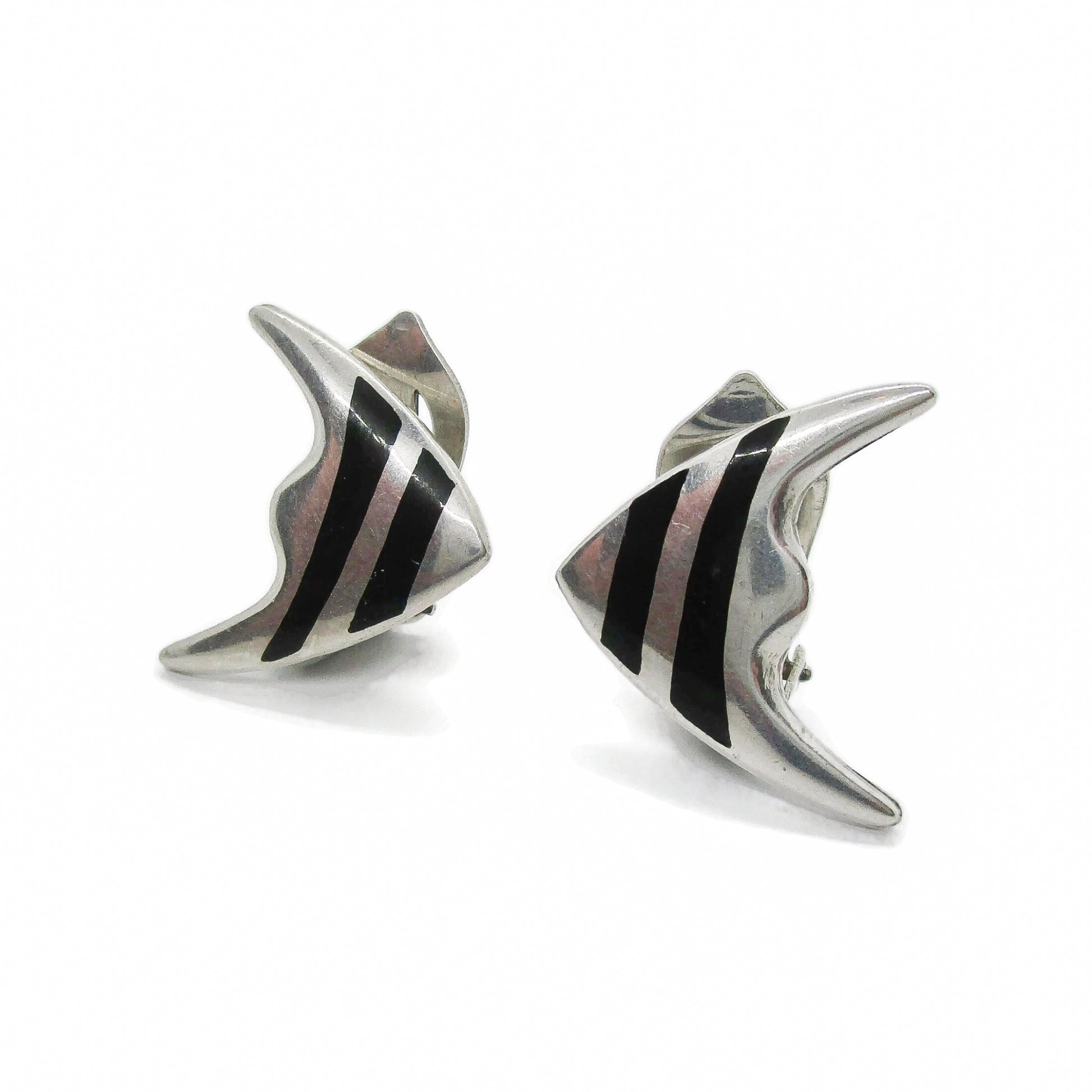 Angled view of a pair of Meka sterling silver striped fish clip on earrings