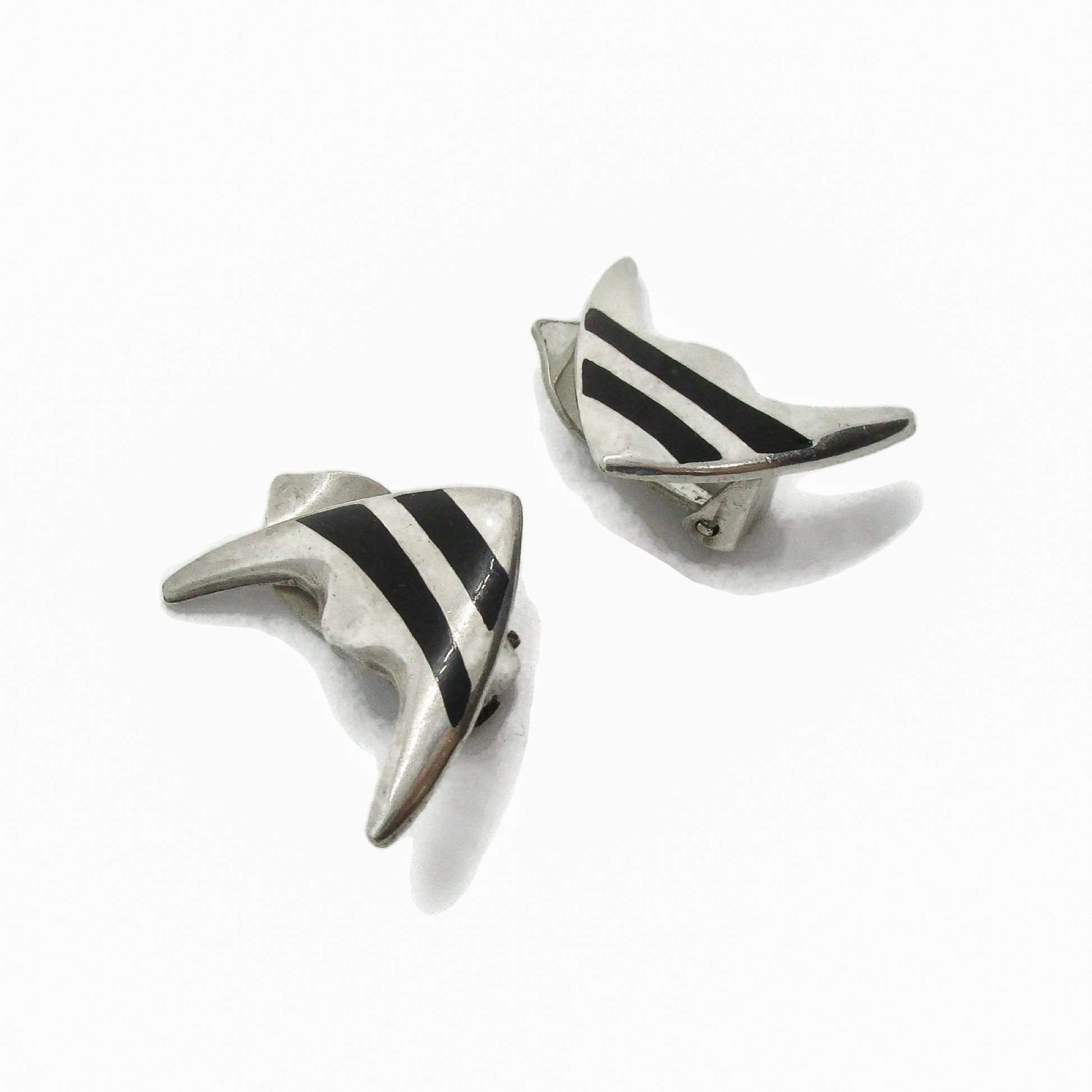 A pair of Meka sterling silver striped fish clip on earrings shown on an angle