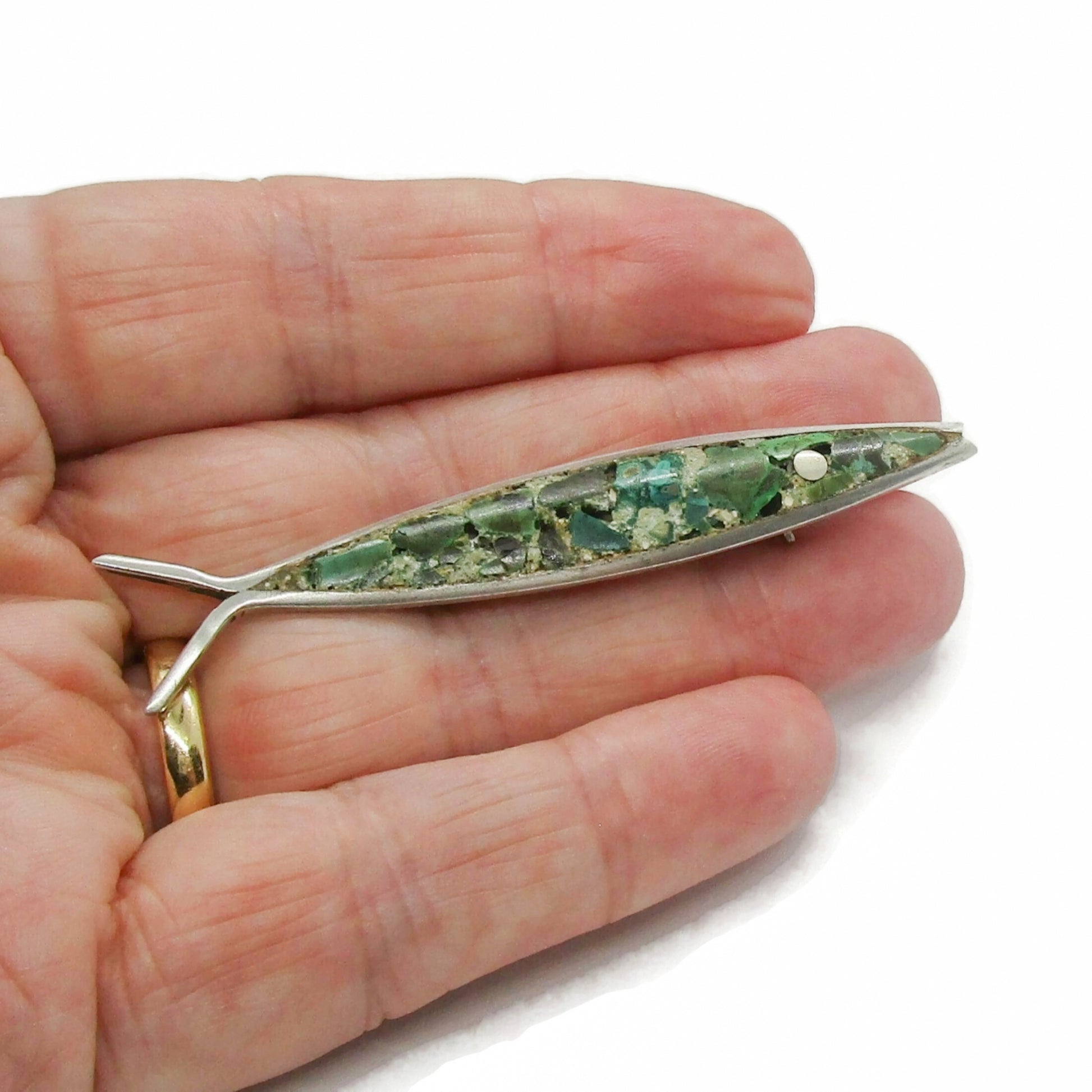 Mexican sterling silver and crushed turquoise fish brooch shown held in a hand