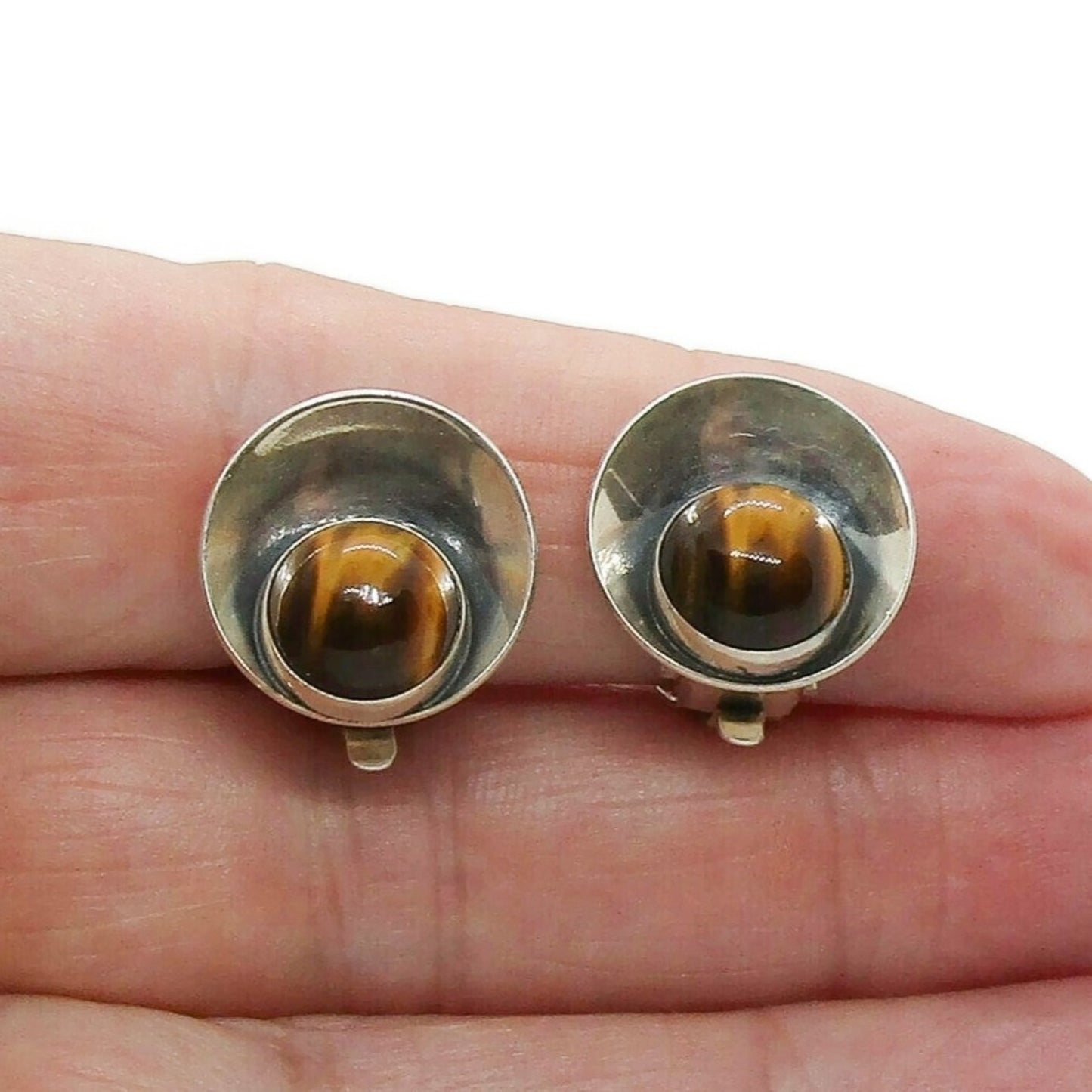 Pair of Niels Erik From Denmark sterling silver and tigers eye clip on earrings shown held in a hand