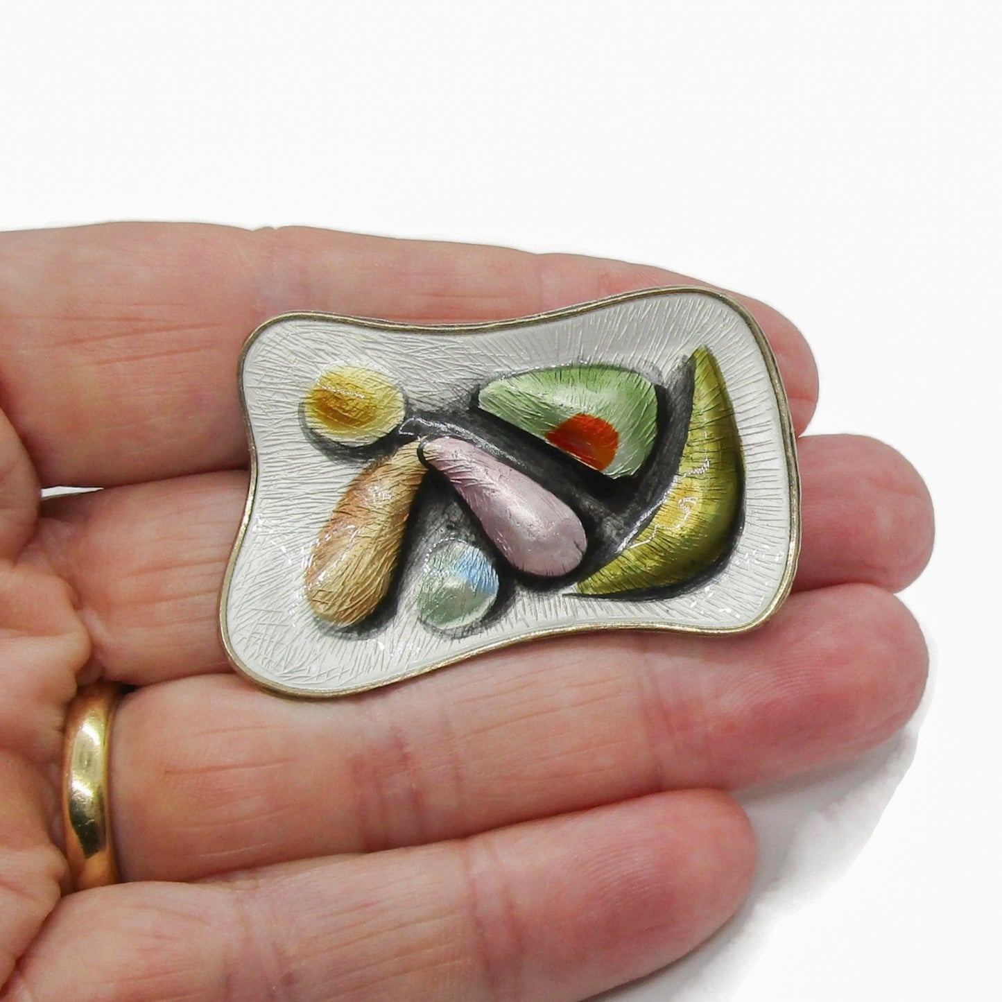 Oystein Balle Norway colourful enamel and sterling silver brooch shown held in a hand