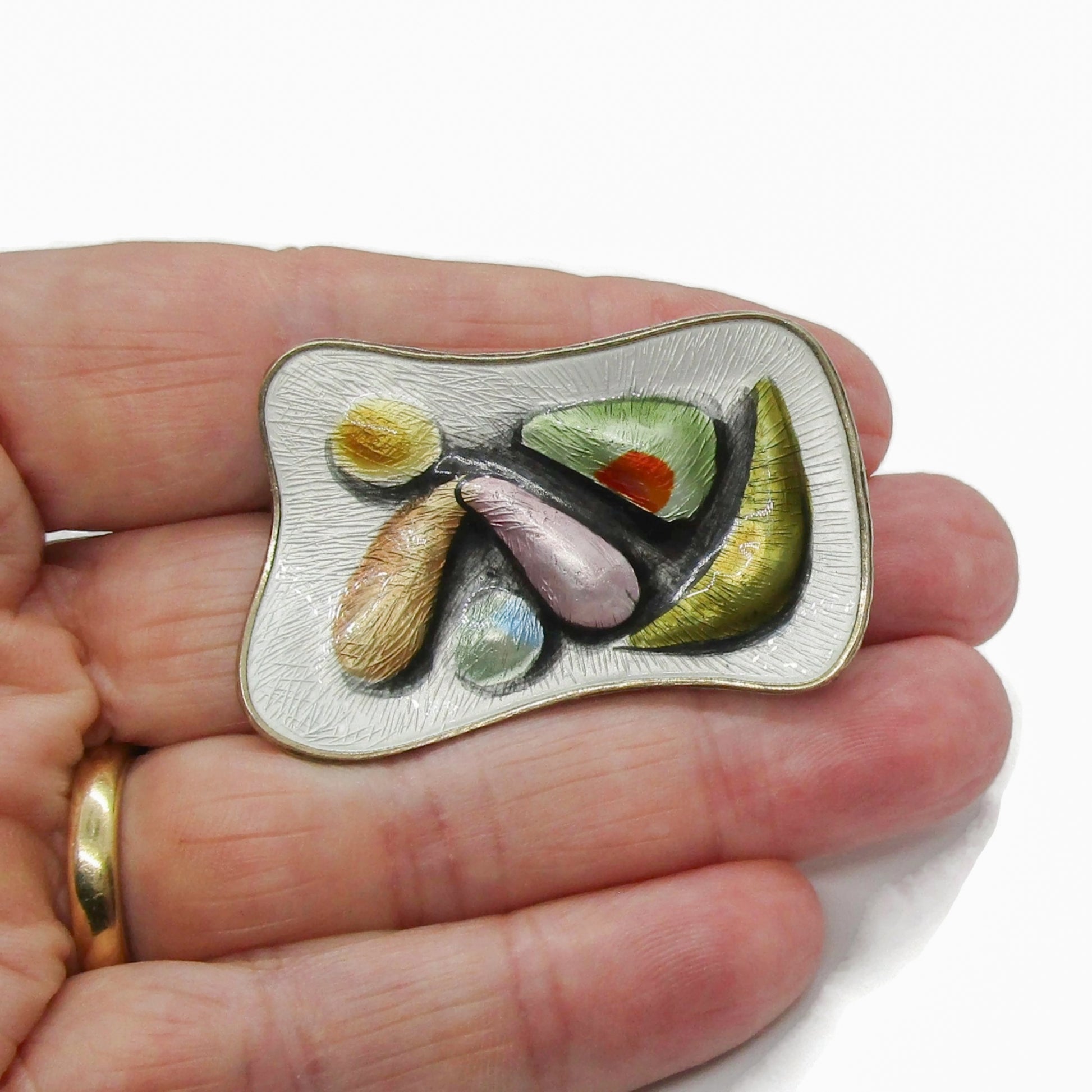 Oystein Balle Norway colourful enamel and sterling silver brooch shown held in a hand