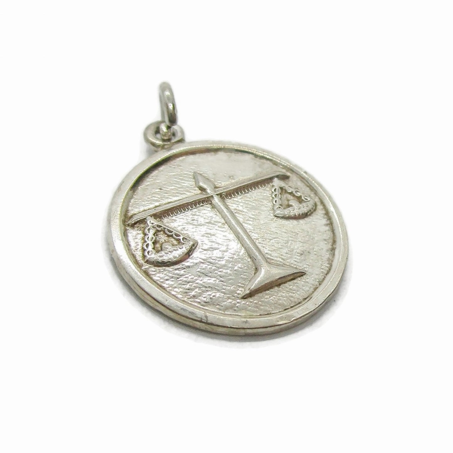 Angled view of a small vintage sterling silver Libra pendant