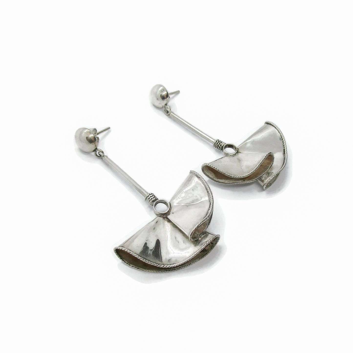 Angled view of a pair of large sterling silver fan-shaped earrings for pierced ears