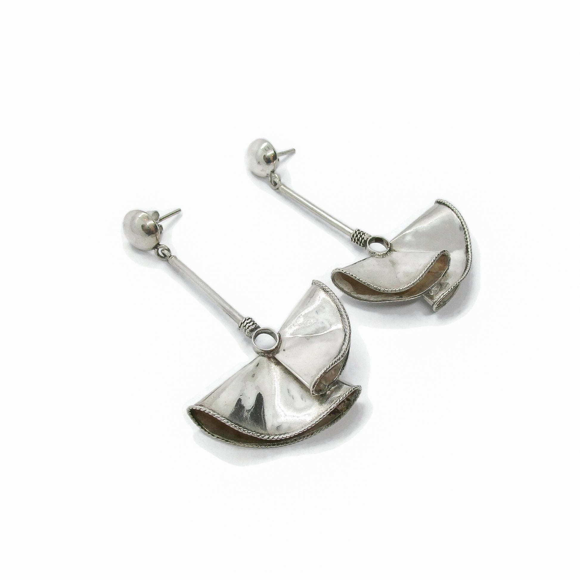Angled view of a pair of large sterling silver fan-shaped earrings for pierced ears