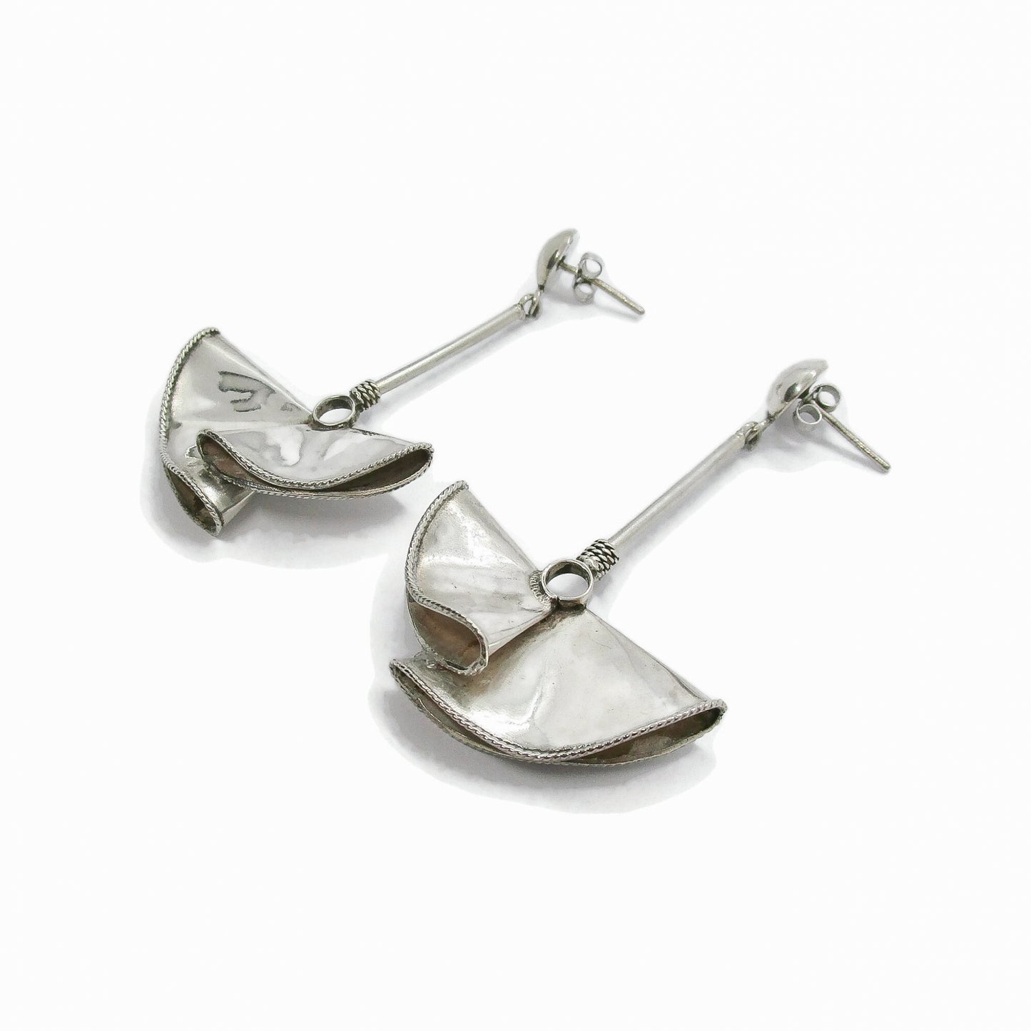 A pair of large sterling silver fan-shaped earrings for pierced ears shown on an angle