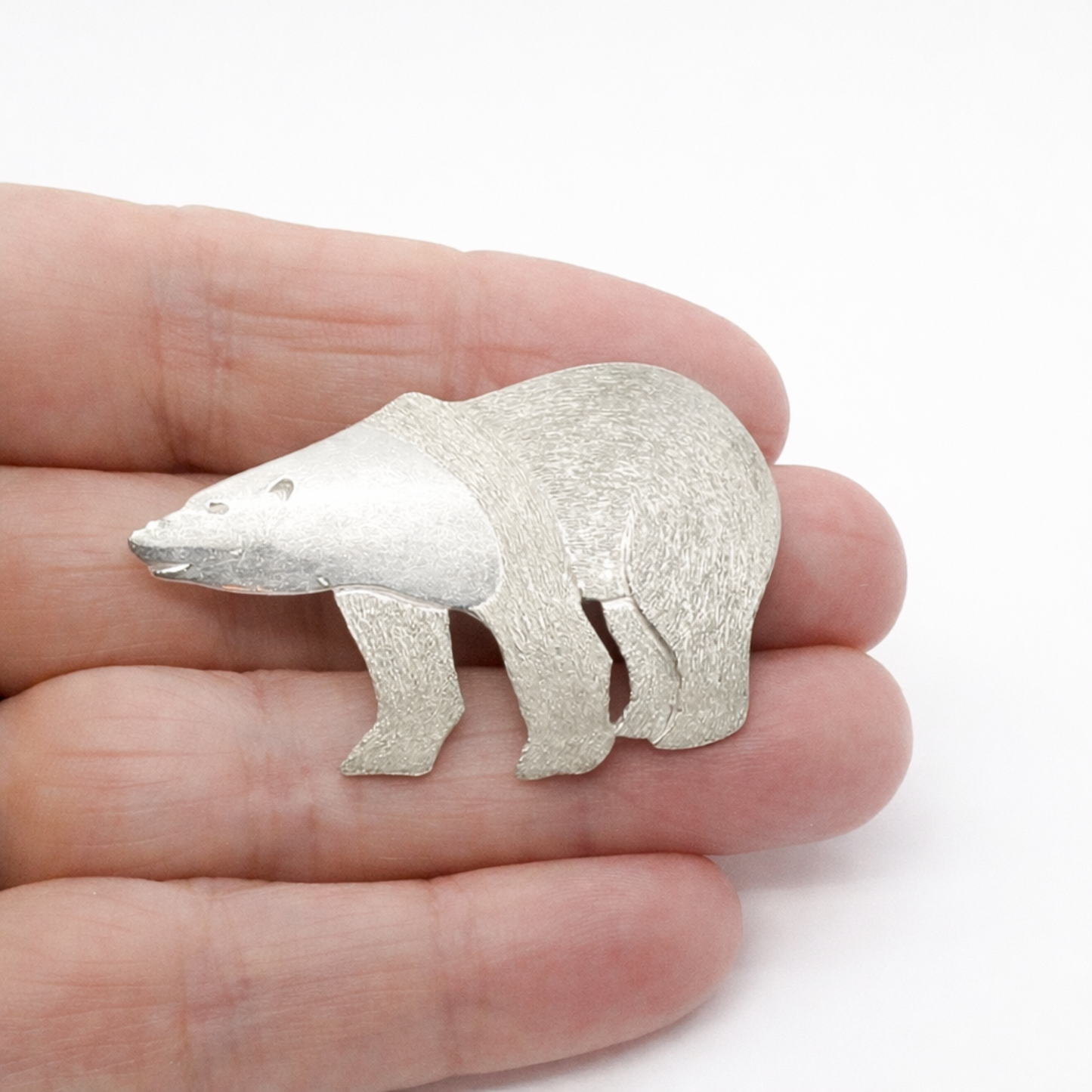 Sterling silver polar bear brooch shown held in hand