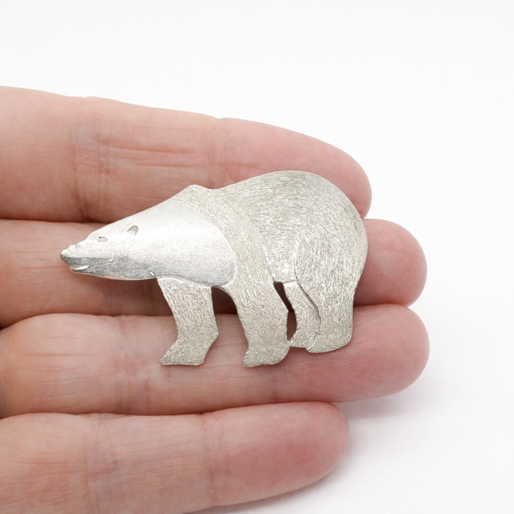 Sterling silver polar bear brooch shown held in hand