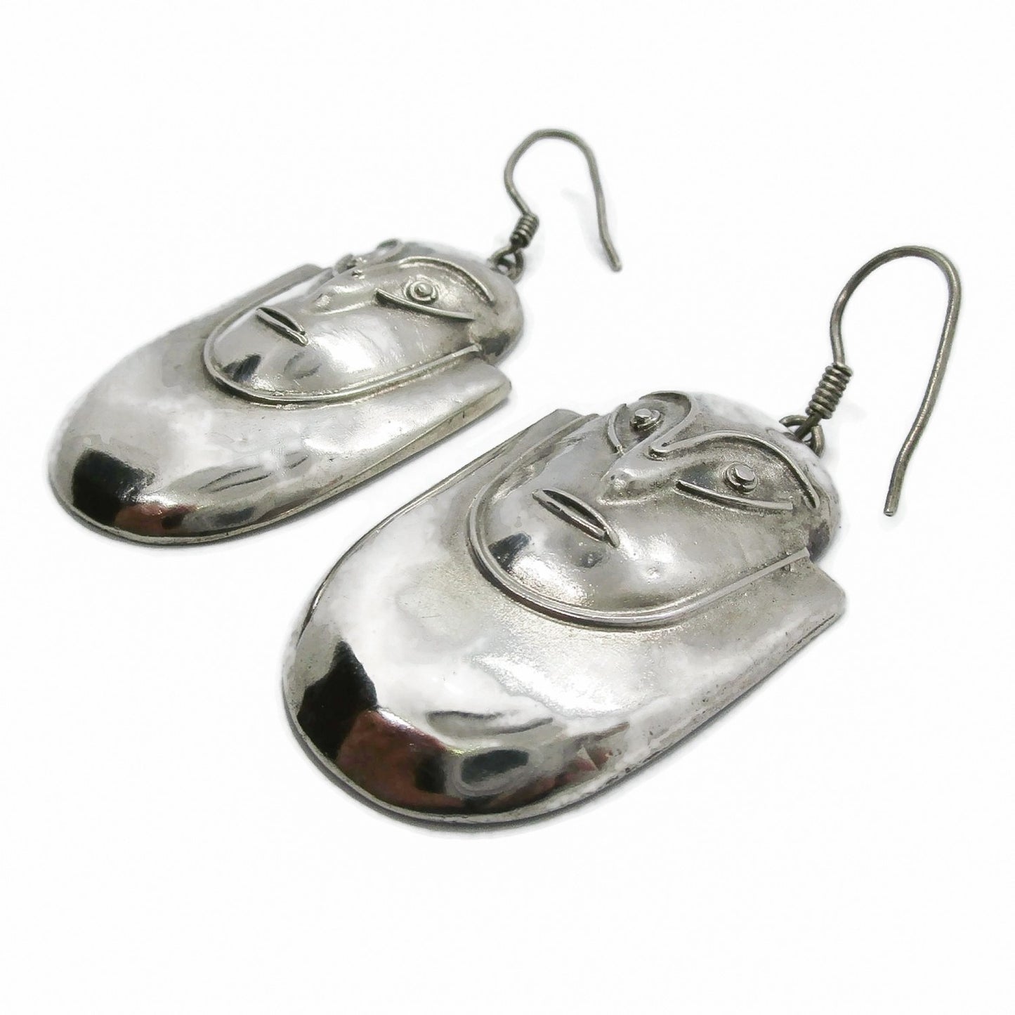 A pair of vintage big sterling silver face shaped dangle earrings seen from the bottom