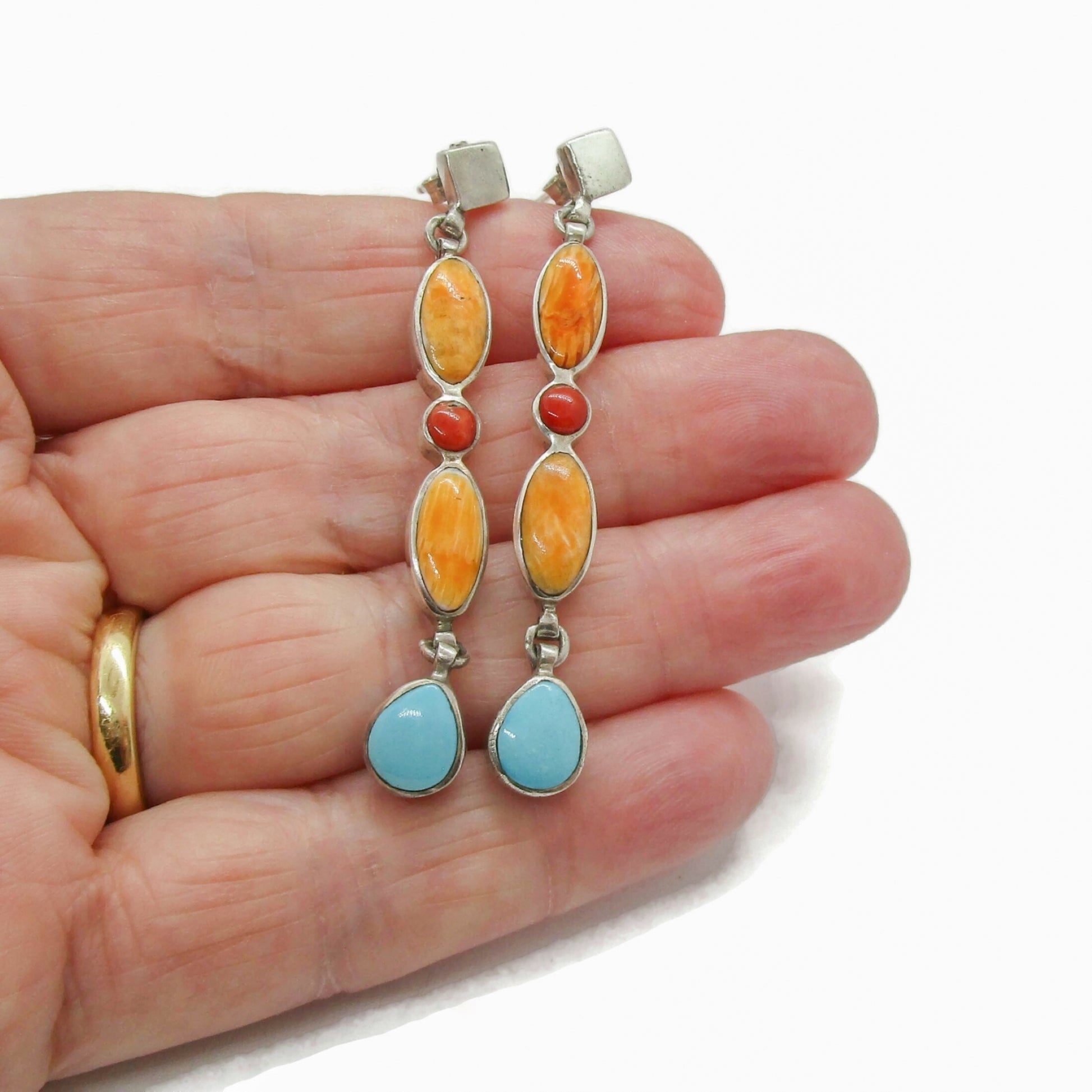 A pair of sterling silver and semi precious gemstone dangle earrings shown held in a hand