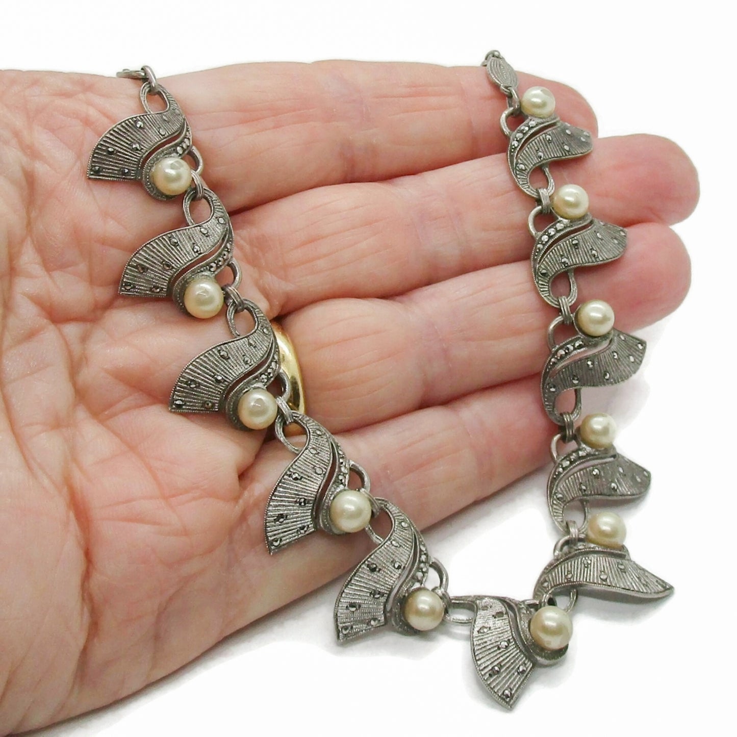 A Theodor Fahrner Germany sterling silver, marcasite and pearl necklace held in a hand