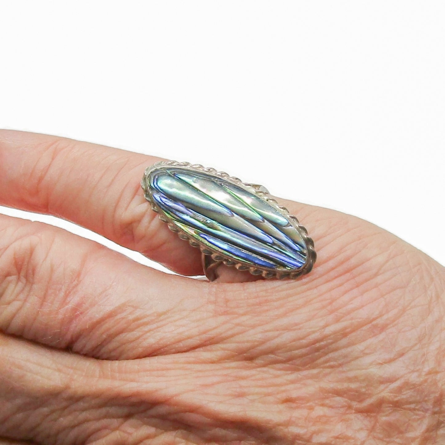 An oval sterling silver and paua shell ring by Ataahua New Zealand shown worn on a finger