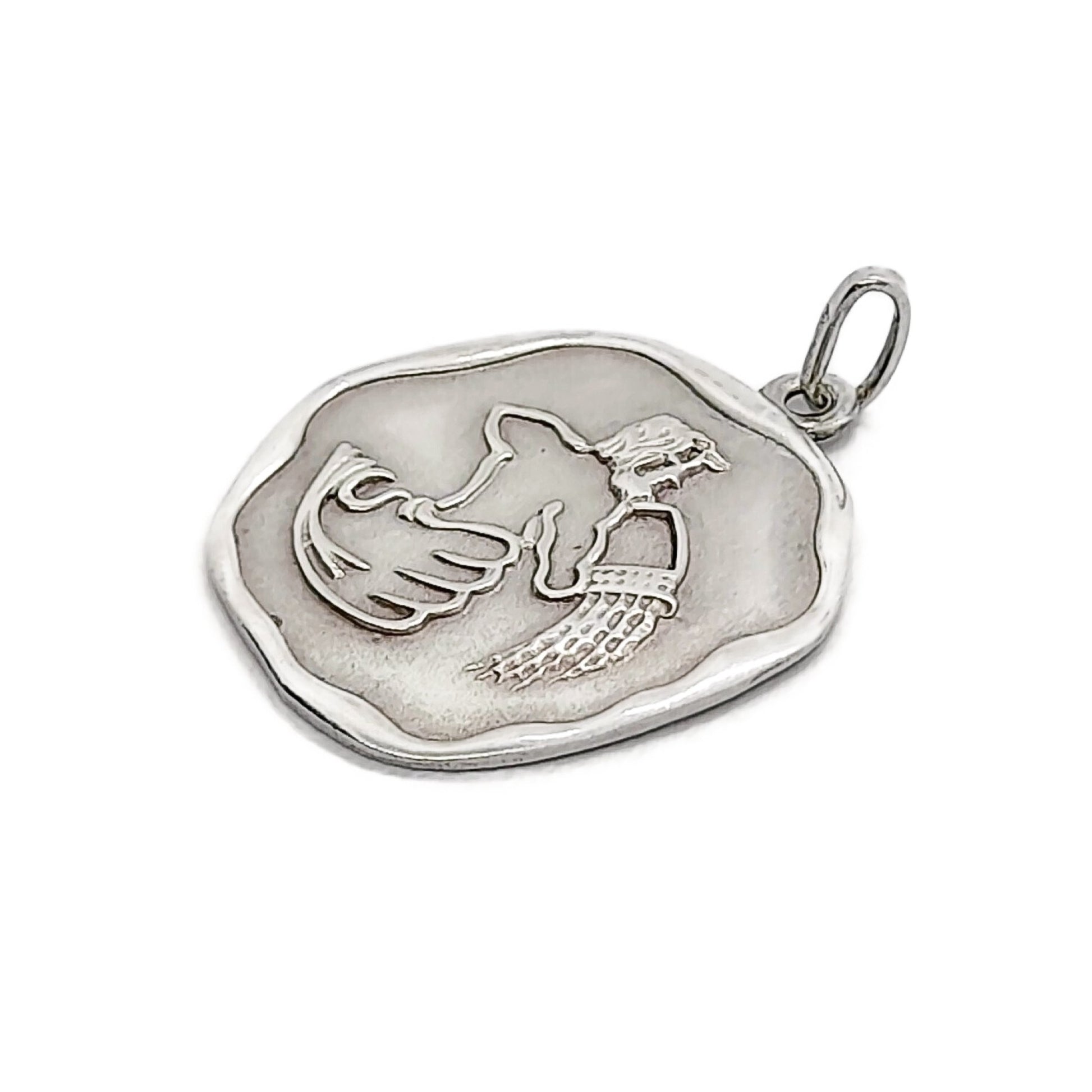 Side view of a vintage sterling silver Aquarius pendant