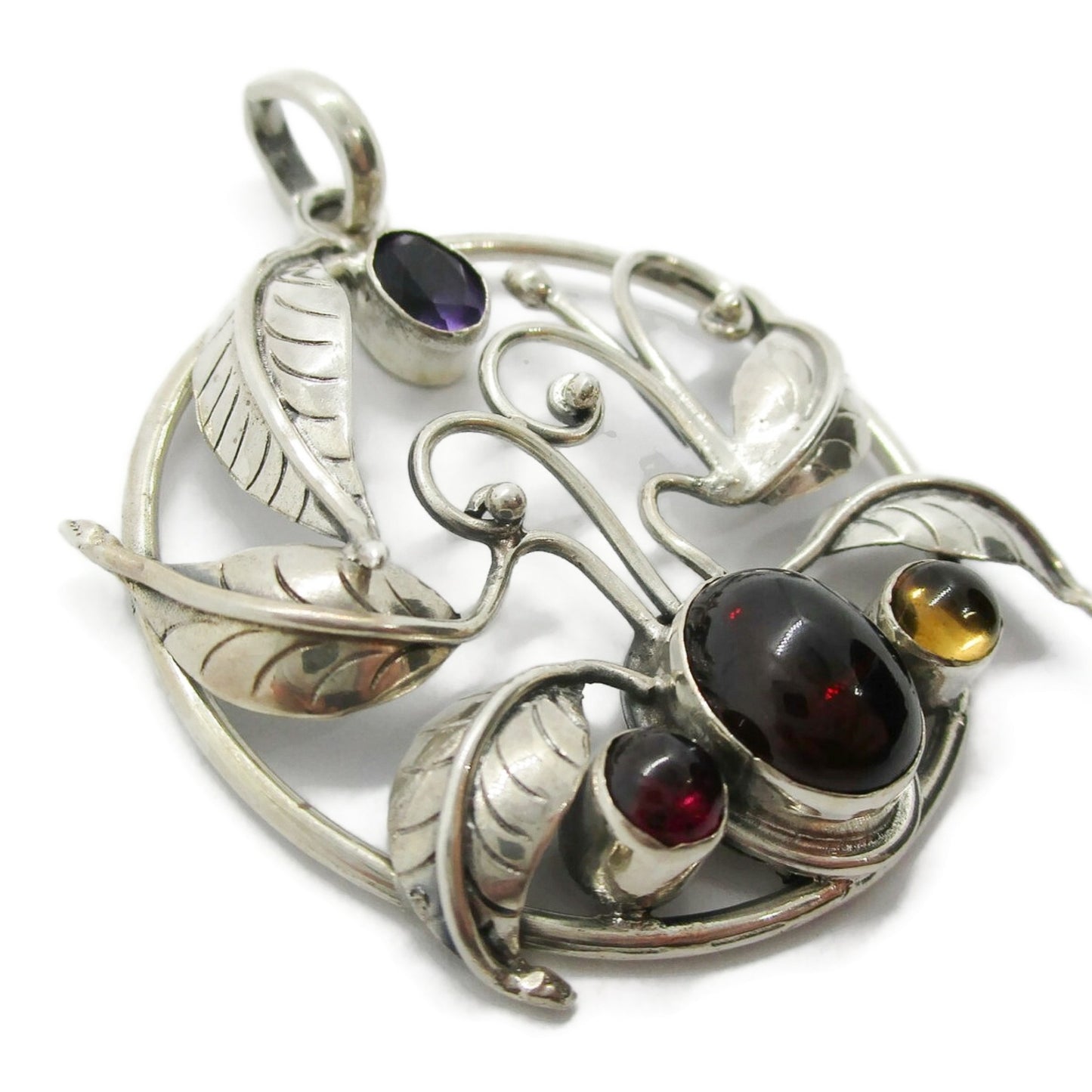 Close up view of a large vintage sterling silver and gemstone floral design pendant
