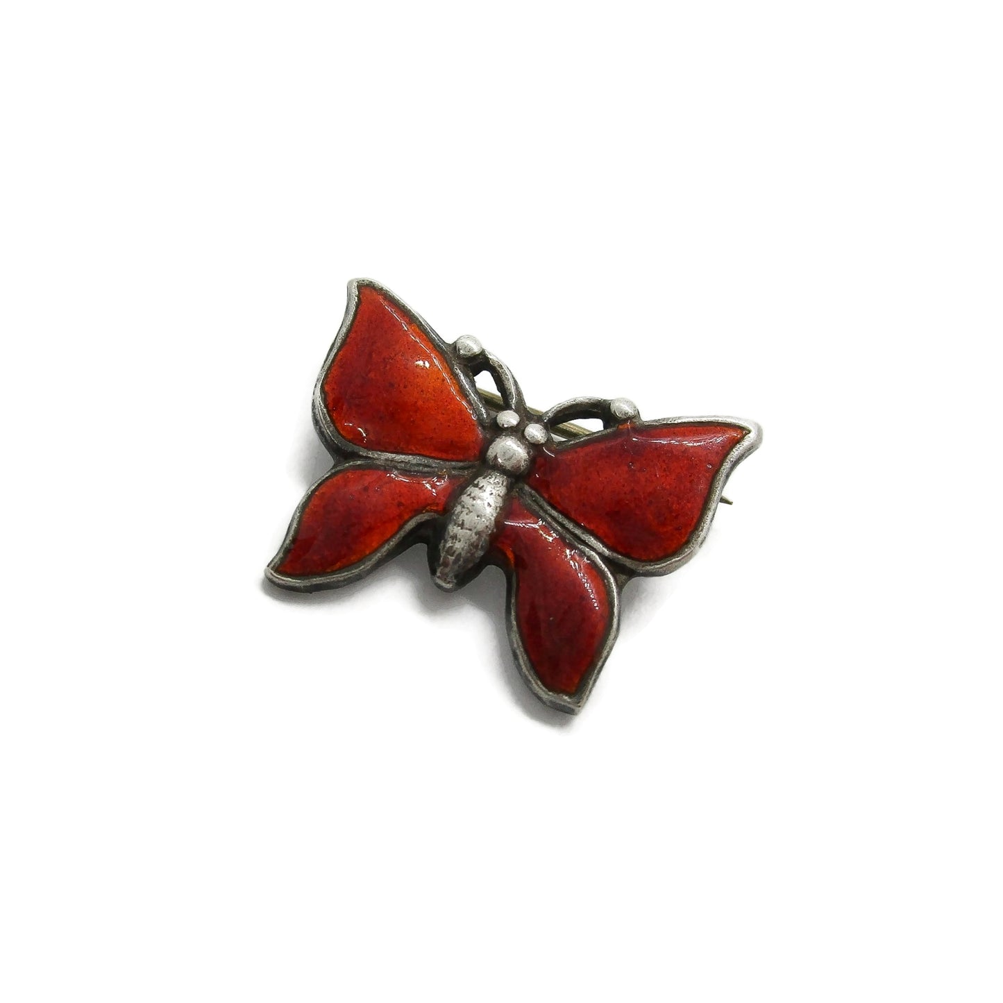 Small vintage red enamel sterling silver butterfly brooch seen at an angle