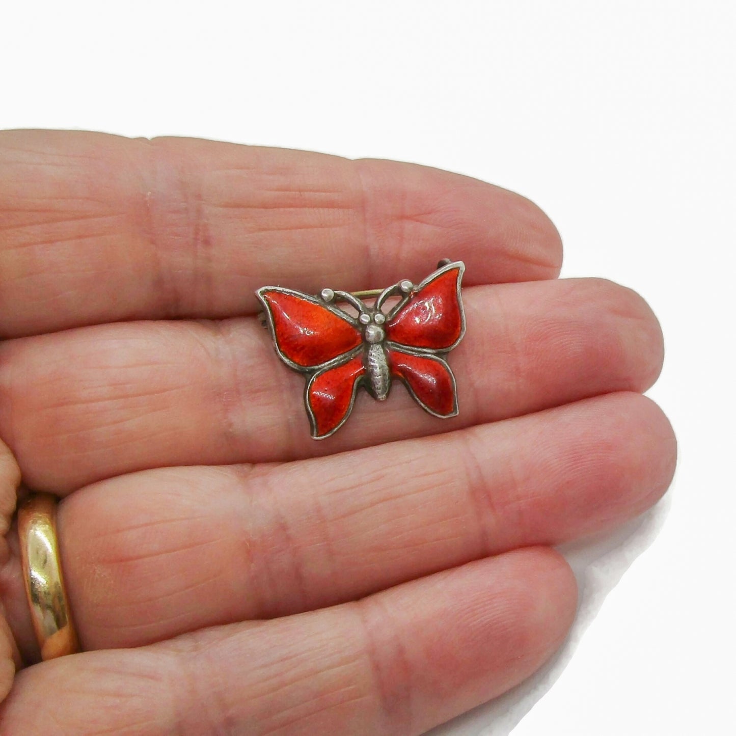 Small vintage red enamel sterling silver butterfly brooch shown held in a hand